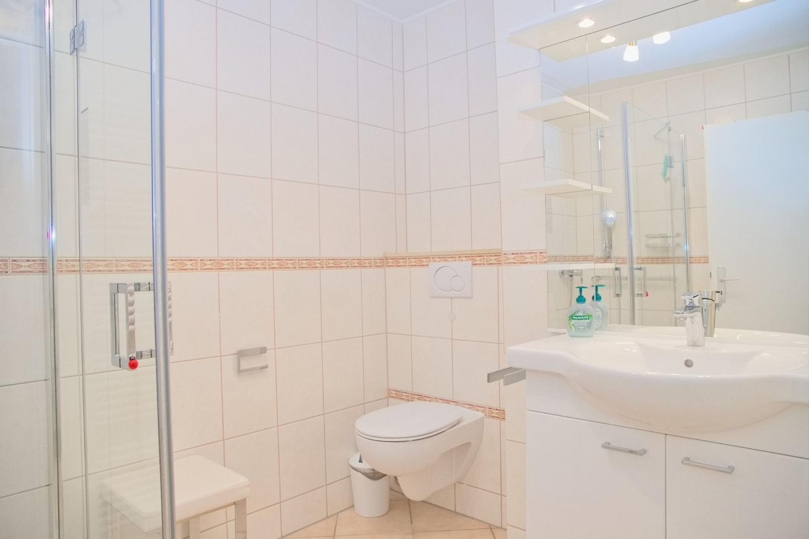 Badezimmer mit Dusche, Toilette und Waschbecken mit Spiegel.