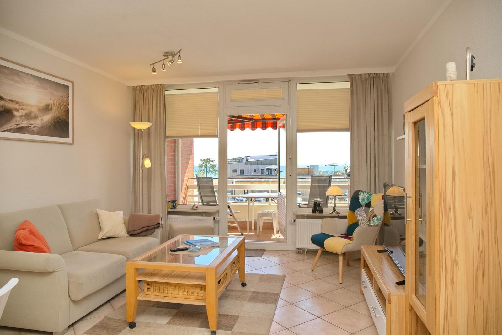 Wohnzimmer mit Sofa, Couchtisch und Balkonansicht. Holzmöbel und Fensterfront.