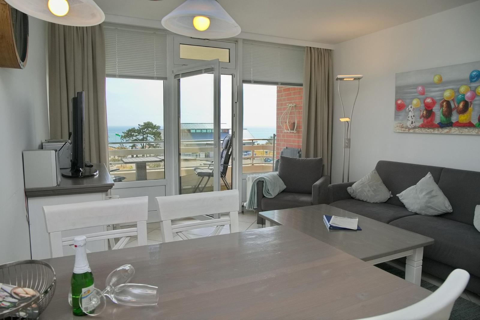 Wohn- und Essbereich mit Blick auf die Terrasse und den Strand. Möbel sind modern und funktional.