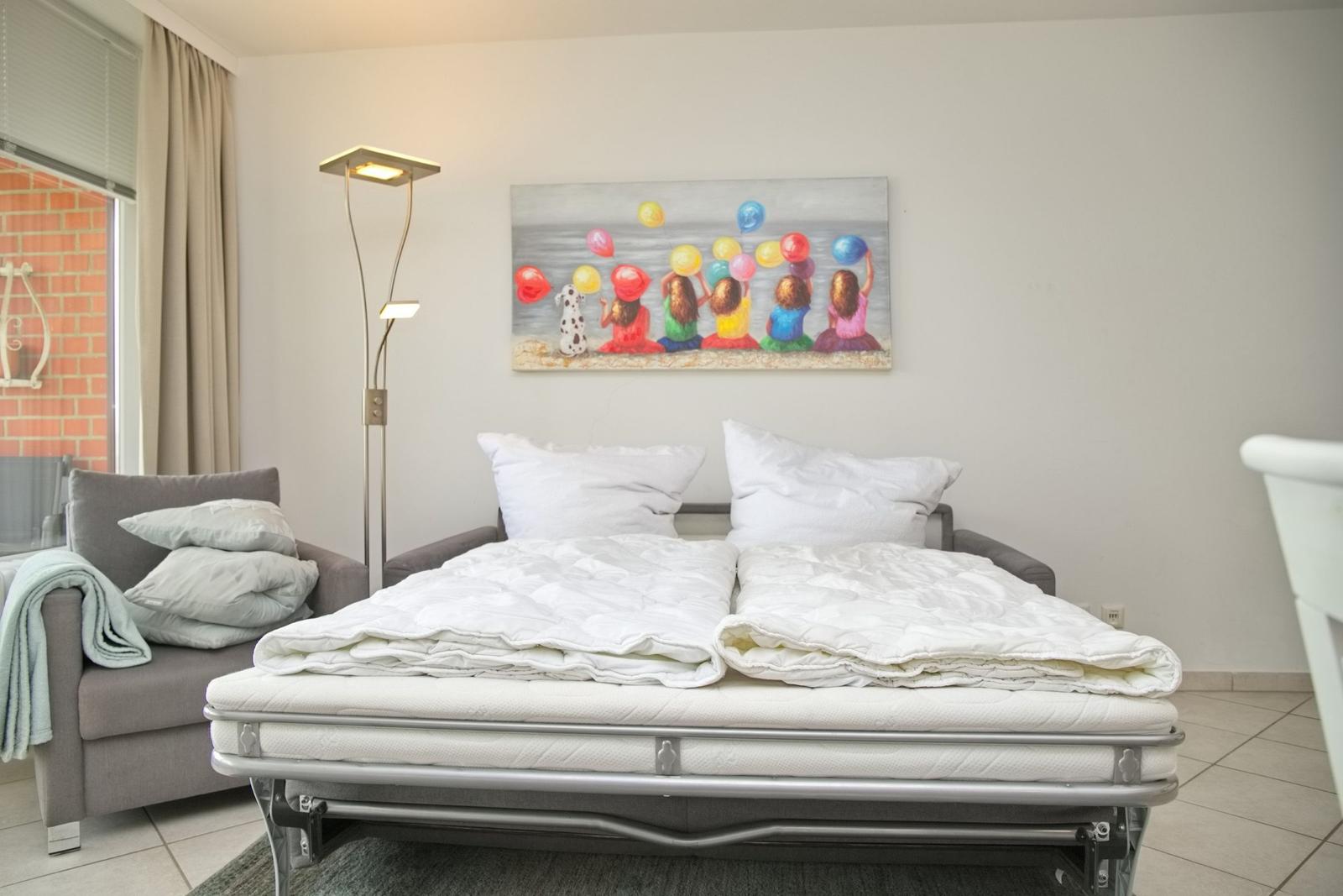 Schlafzimmer mit Bett, Sessel und Wandbild mit Ballons.