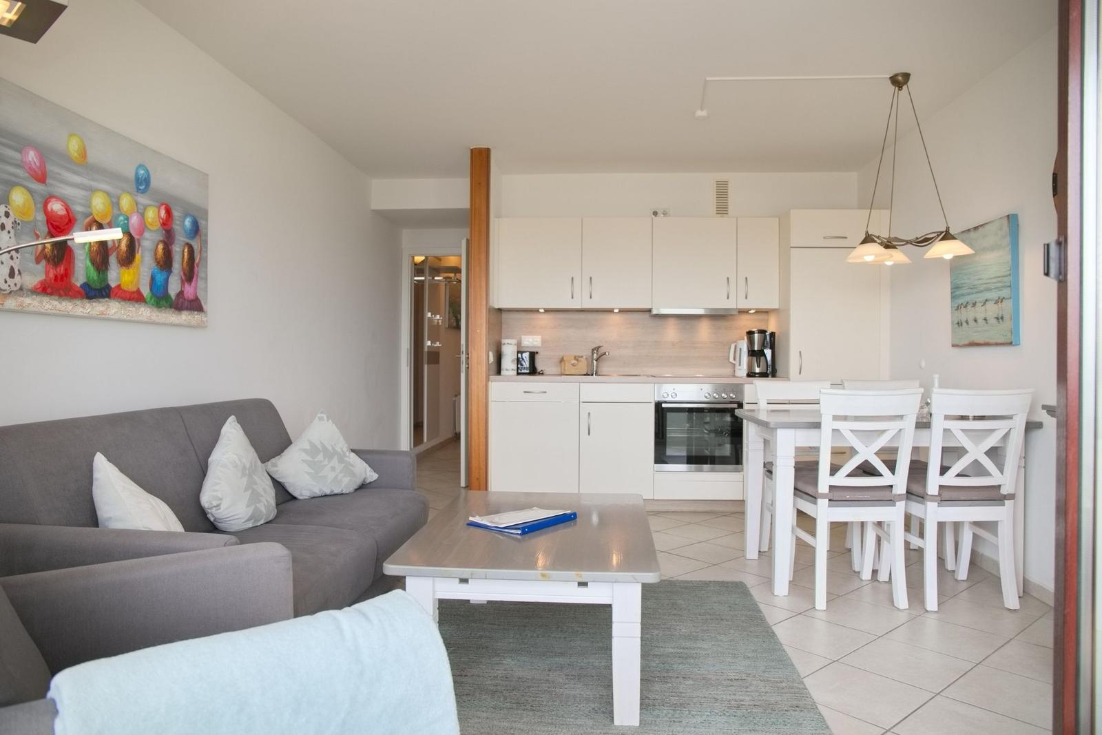 Wohn- und Essbereich mit Küche, Sofa, Esstisch und Wandbild.