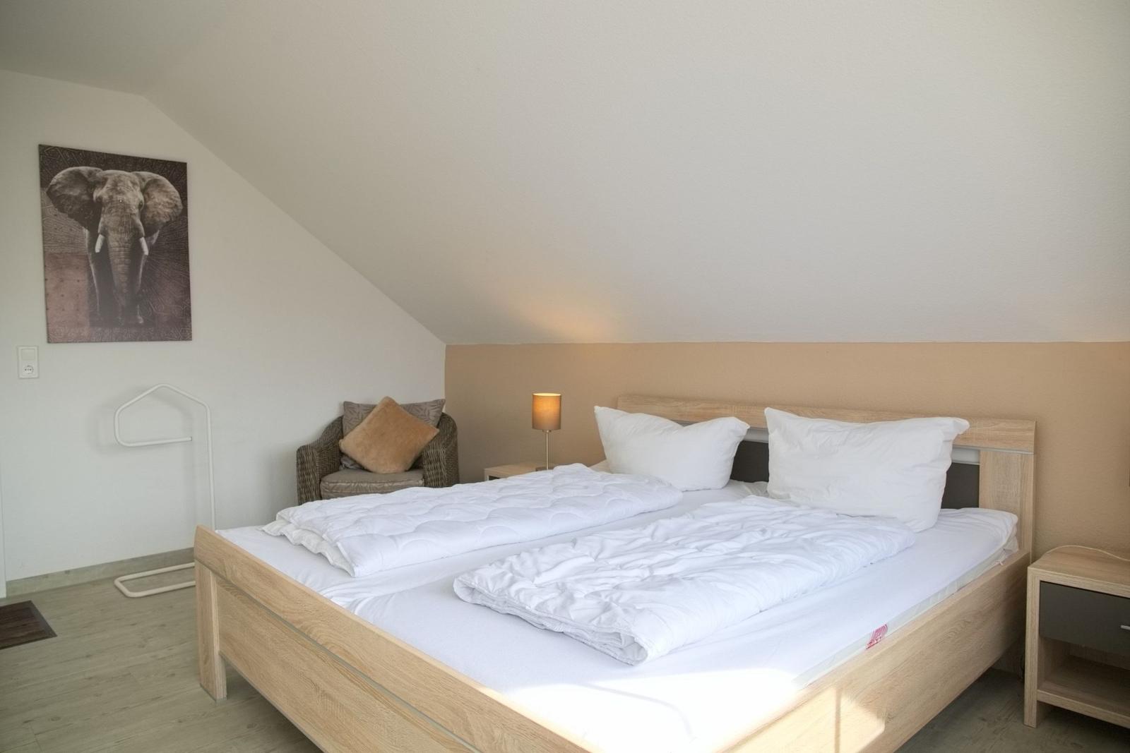 Schlafzimmer mit Doppelbett, Nachttisch und Wandbild eines Elefanten.