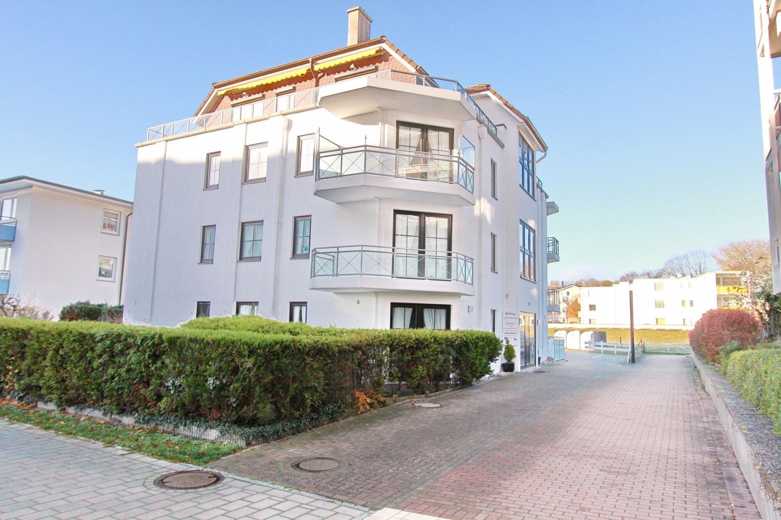 Weißes Mehrfamilienhaus mit Balkonen und begrünter Fassade