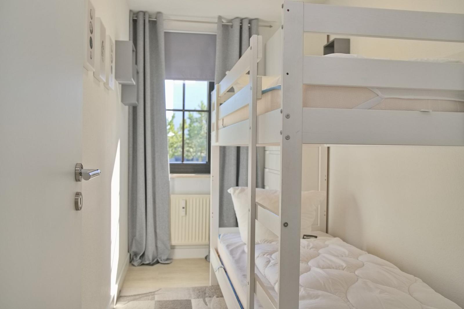 Zimmer mit Doppelstockbett, Fenster und grauen Vorhängen.
