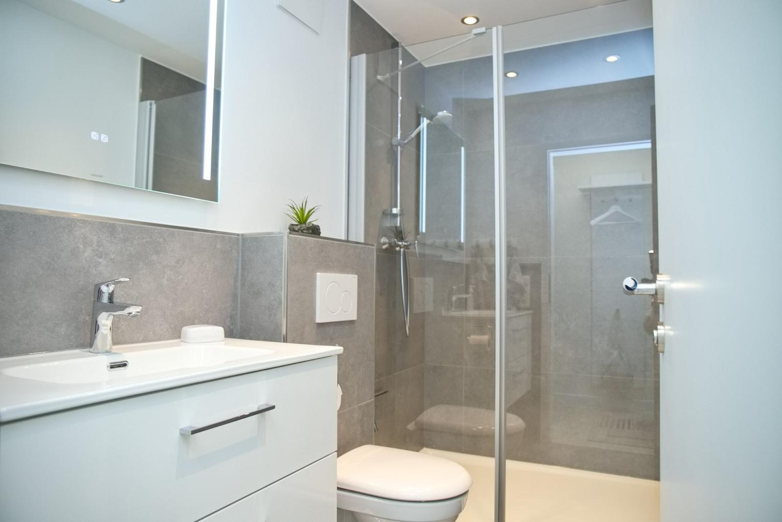 Badezimmer mit Dusche, Waschbecken und Toilette.