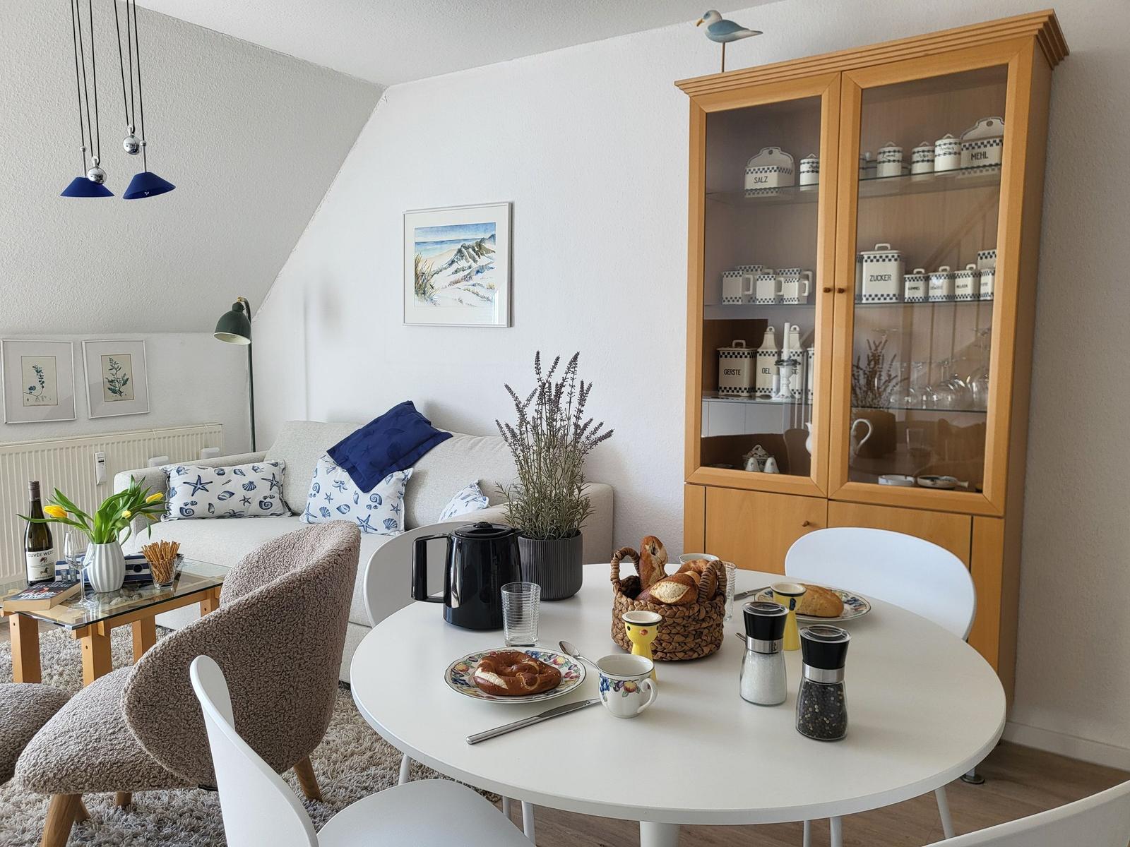 Esszimmer mit runden Tisch, Küchenregal und Sofa mit Kissen.