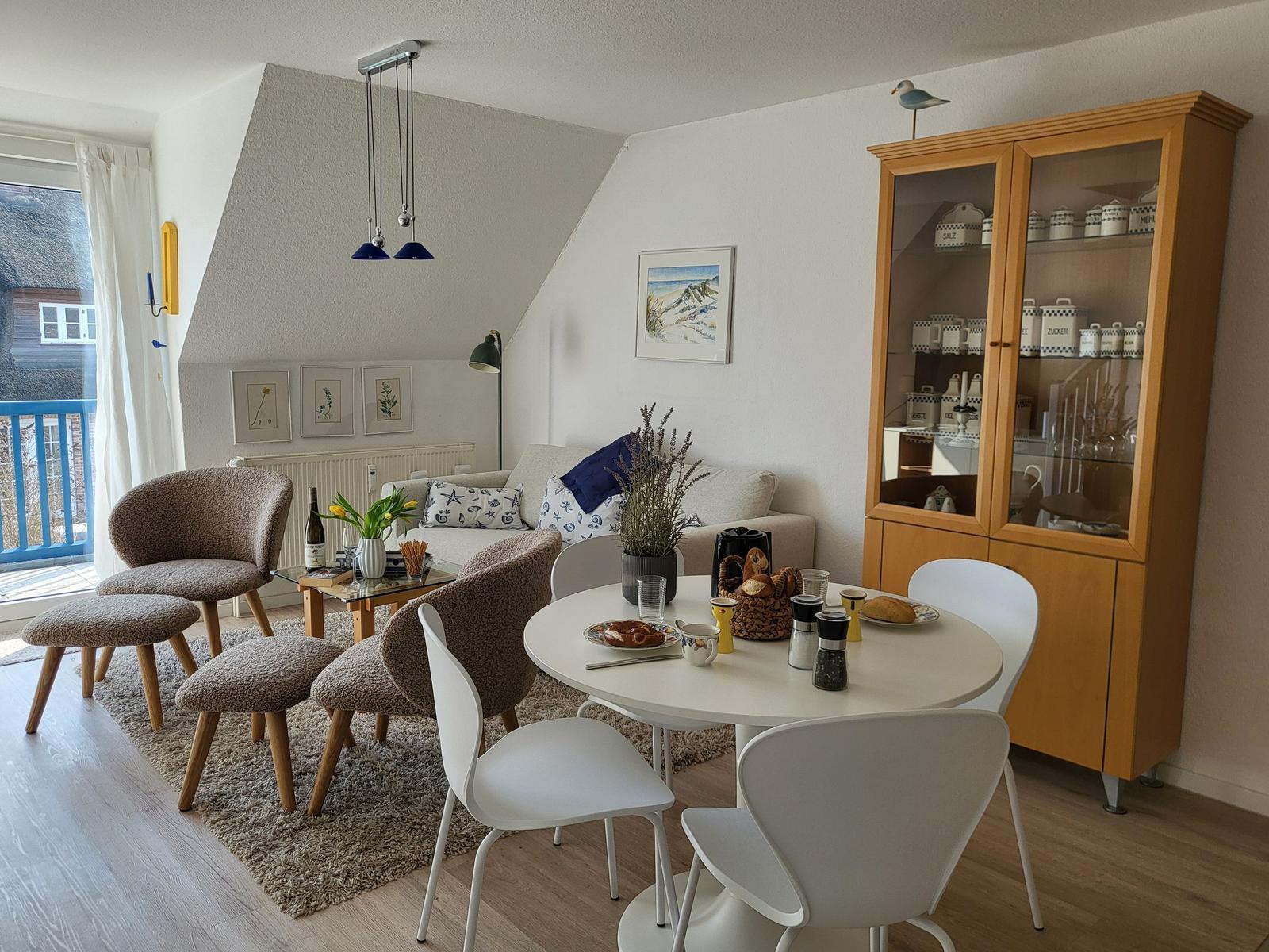 Wohn- und Essbereich mit Sofa, Esstisch und Glasvitrine.