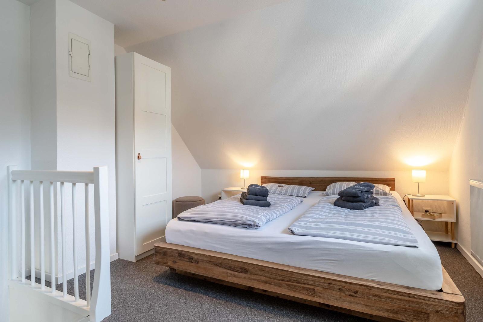 Schlafzimmer mit Doppelbett, zwei Nachttischen und einem Kleiderschrank.
