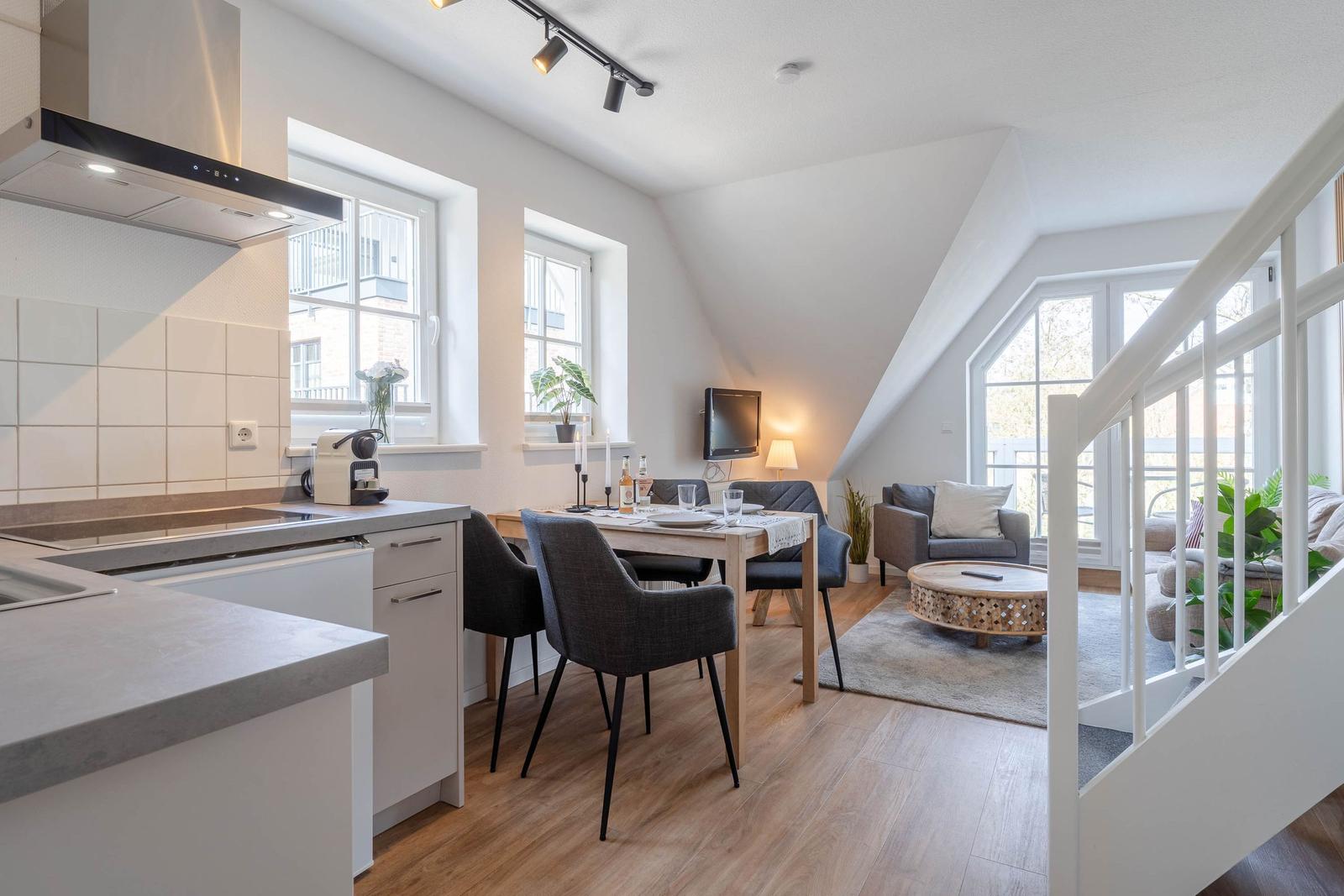 Küche mit Essbereich und Wohnzimmer mit Holzboden und großen Fenstern.