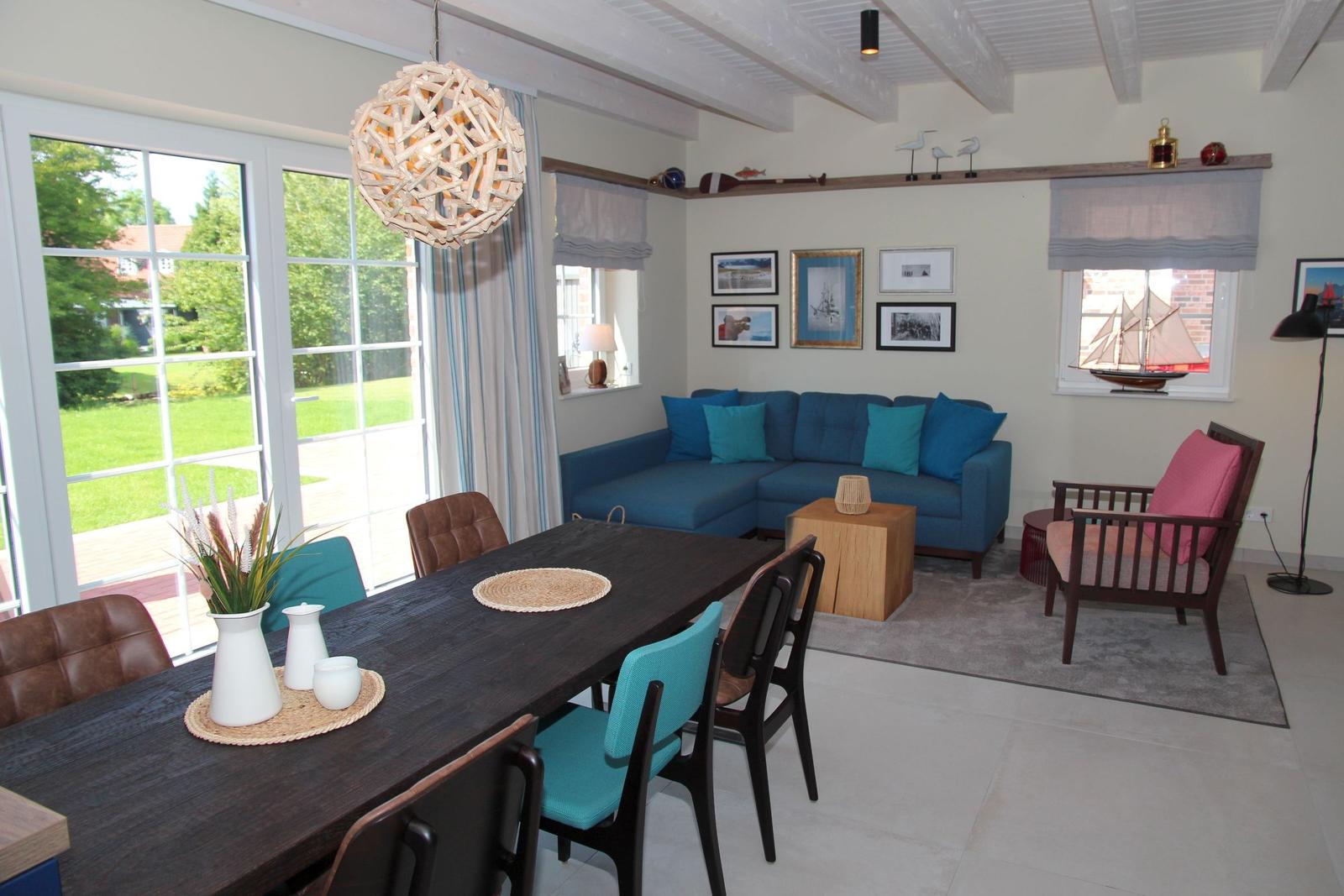 Essbereich mit Tisch und Stühlen. Wohnbereich mit Sofa und Sessel. Fenster zur Terrasse.