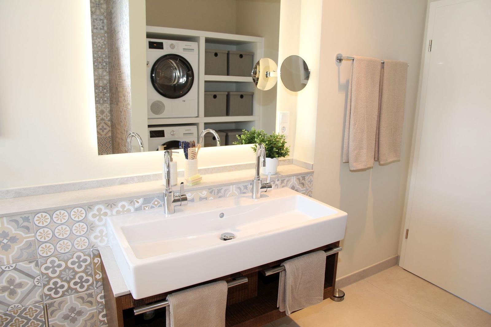 Badezimmer mit Waschmaschine, Spiegel und Handtuchhalter