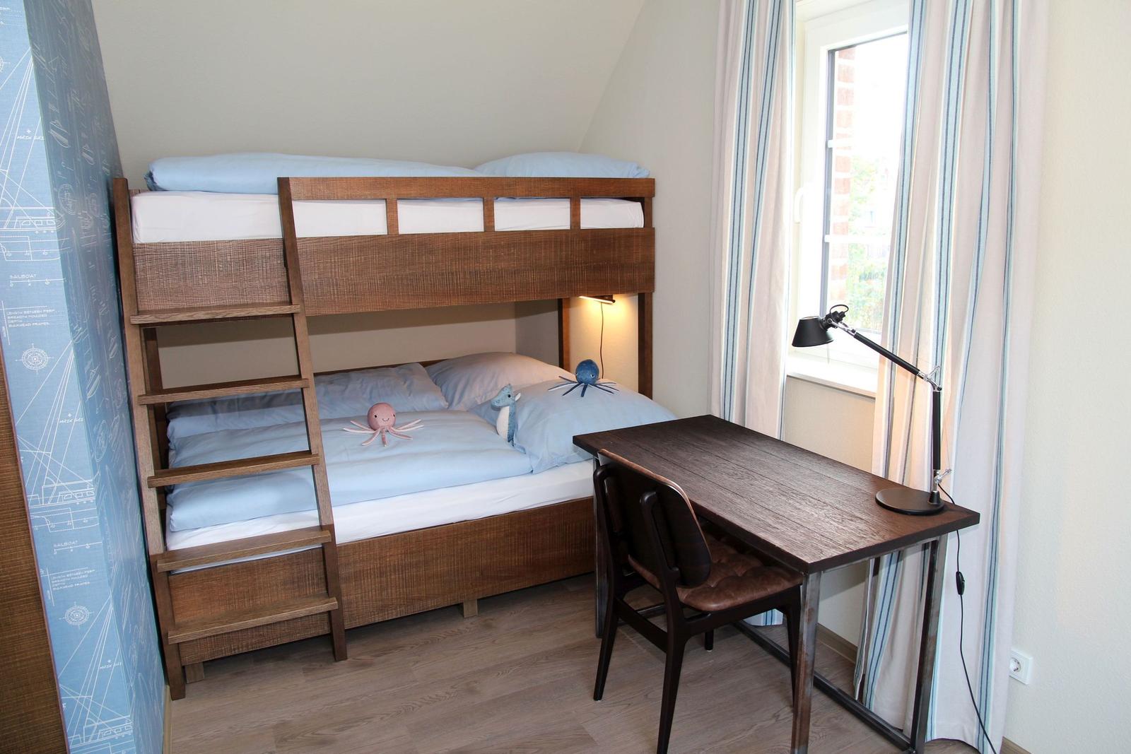 Ein Schlafzimmer mit einem Doppelstockbett, einem Schreibtisch und einem Stuhl.