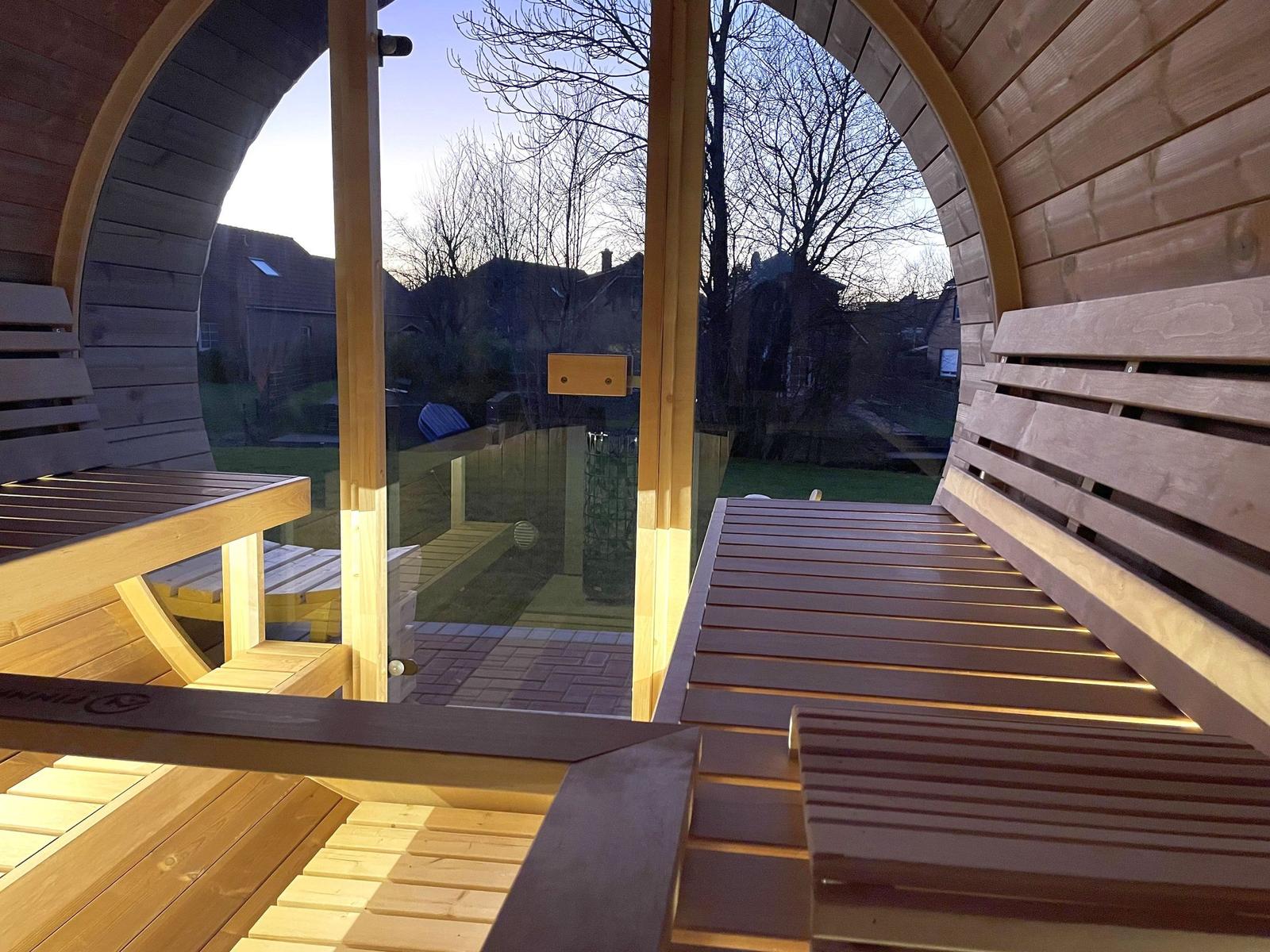 Holzsauna mit Sitzbänken und Blick auf Garten