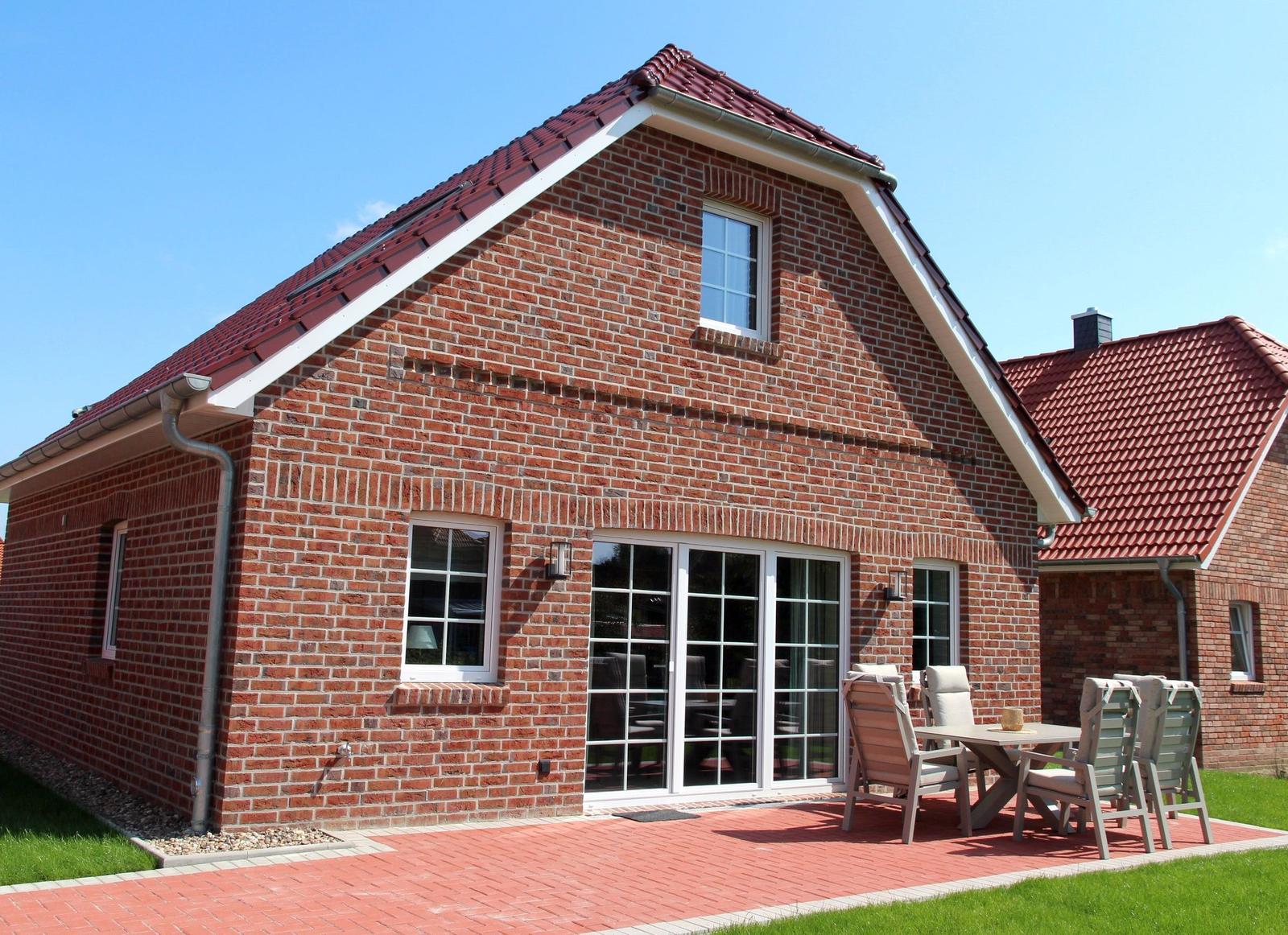 Rotes Ziegelhaus mit Terrasse und Sitzgelegenheiten im Freien.