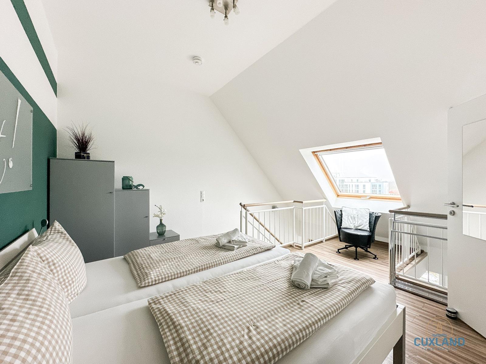 Schlafzimmer mit Dachschrägen, Dachfenster und schwarzem Sessel.