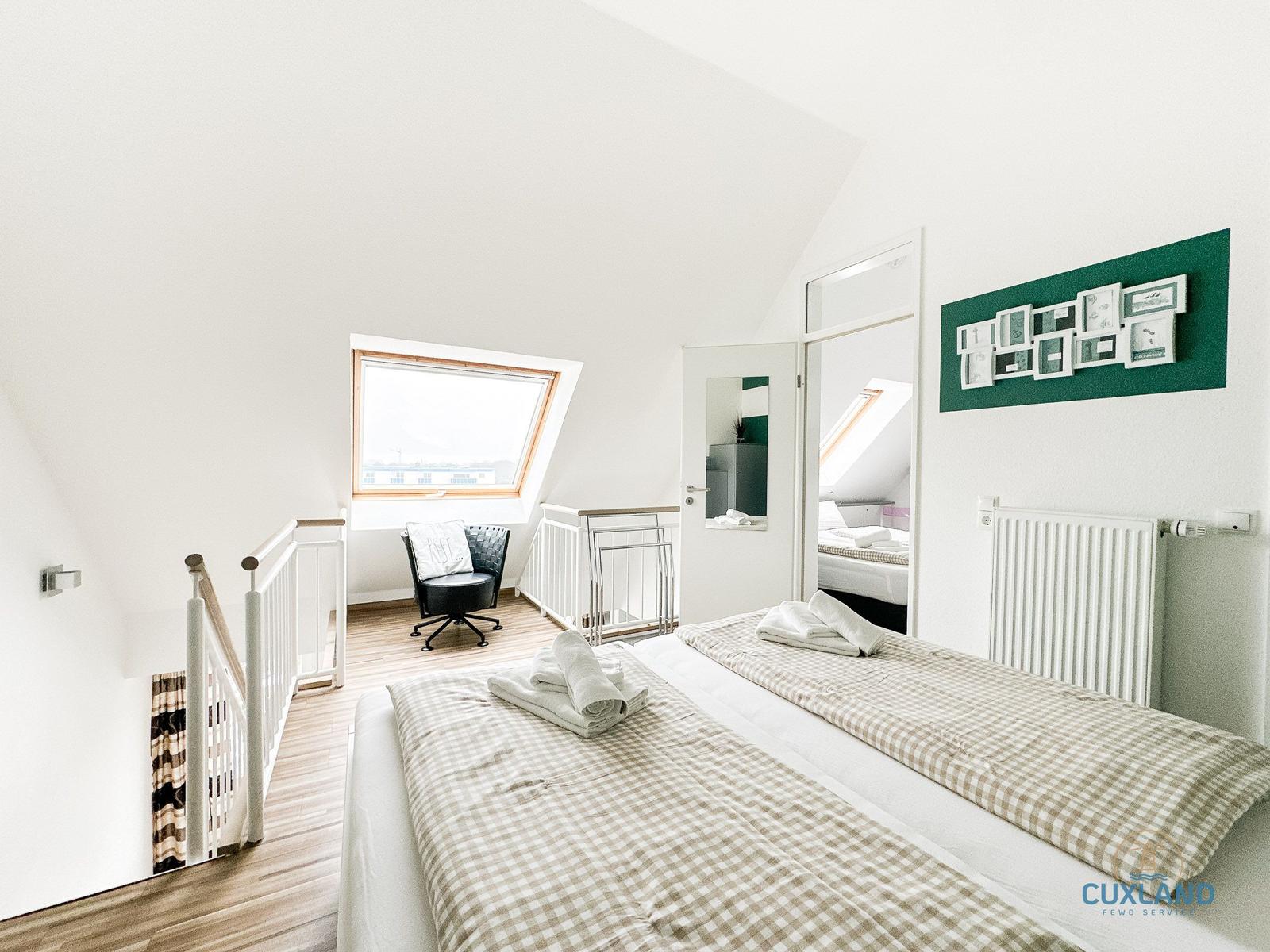 Schlafzimmer mit Dachschrägen, Dachfenster und zwei Betten mit Handtüchern.