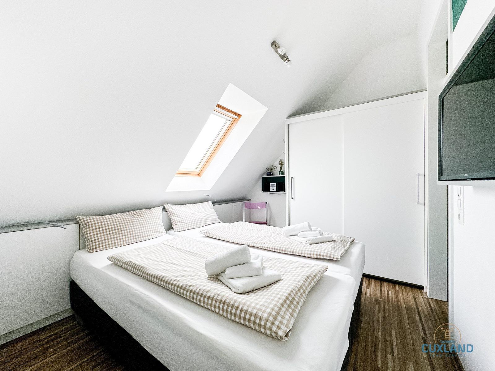 Schlafzimmer mit Dachschräge, Dachfenster, Bett und Kleiderschrank.
