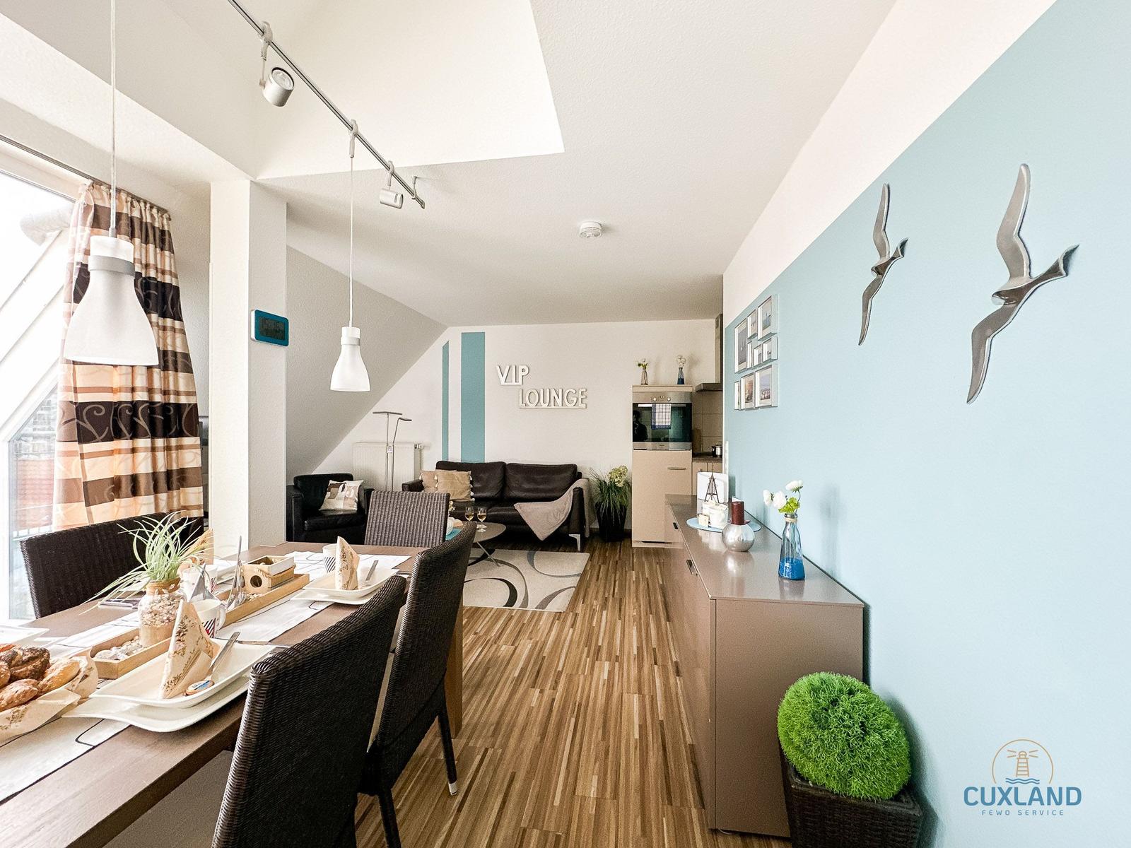 Essbereich mit Tisch und Stühlen, Wohnbereich mit Sofa und Wanddekoration.
