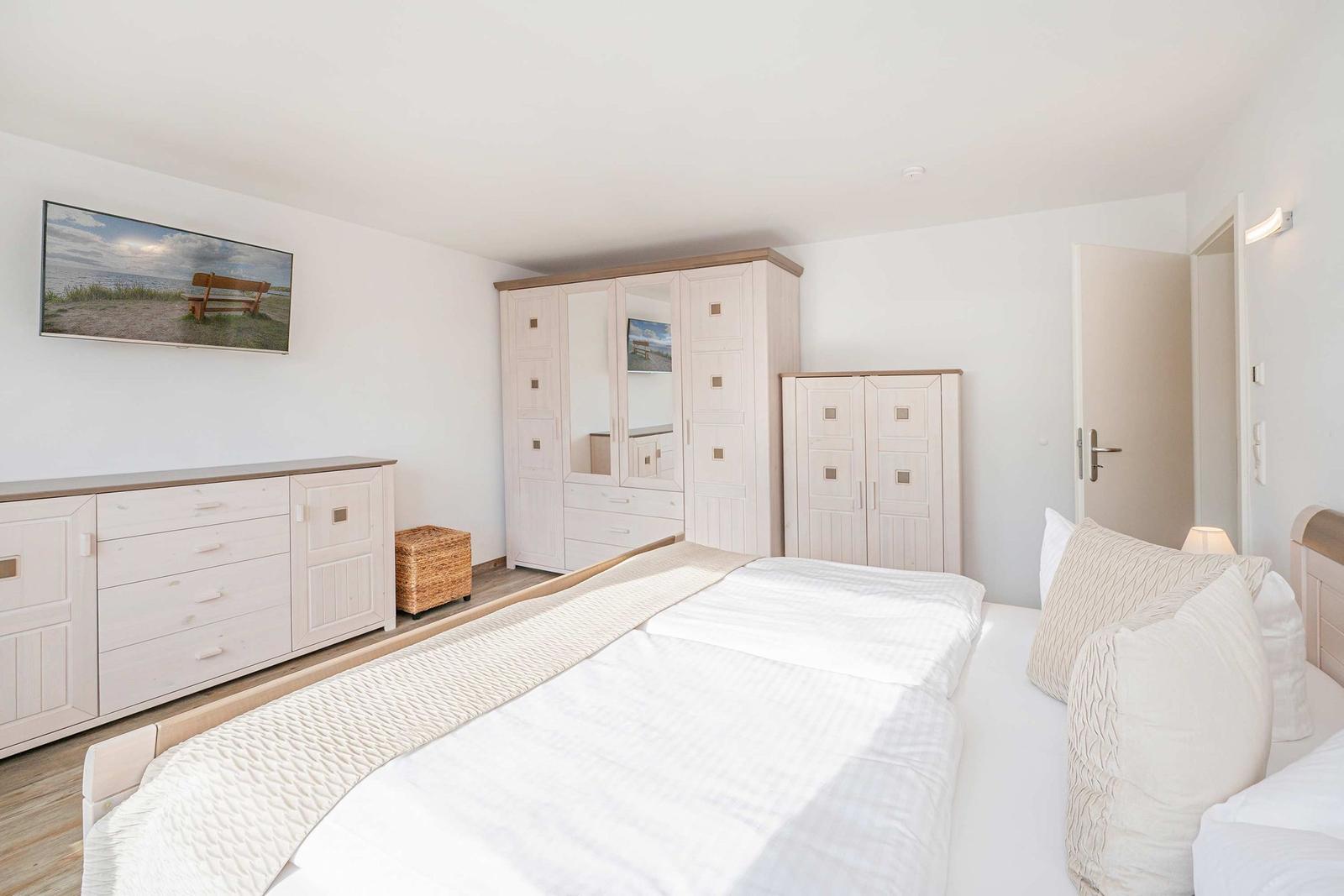 Schlafzimmer mit Bett, Kleiderschränken und Wandbild