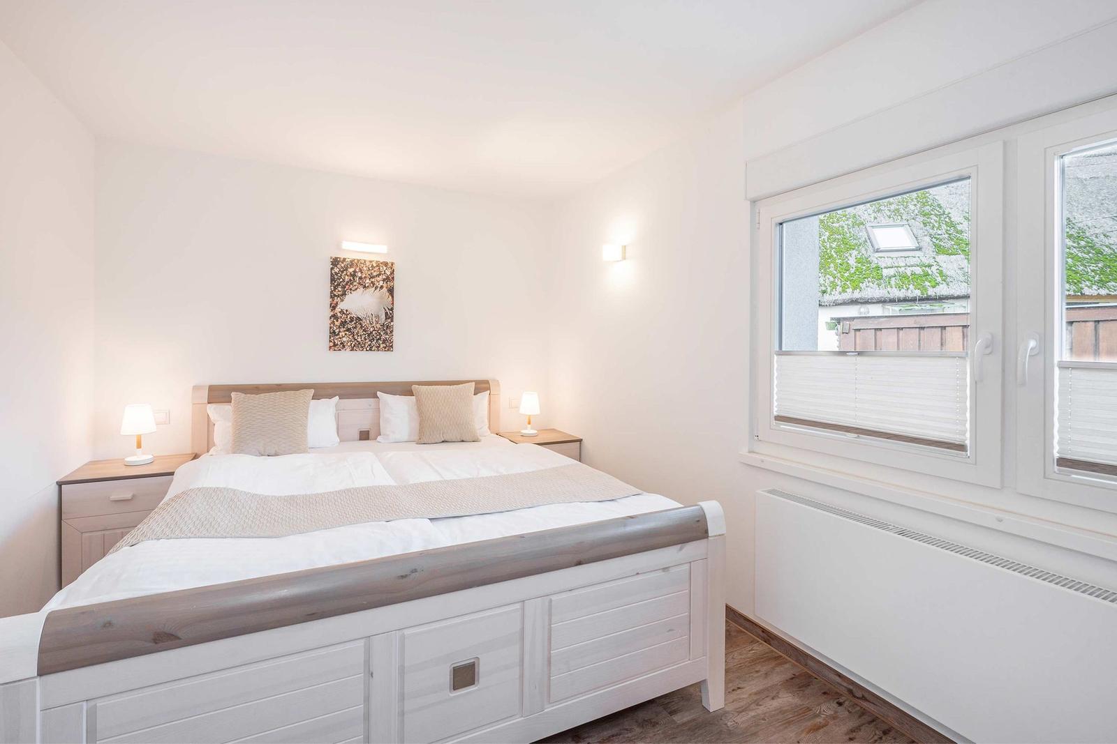 Schlafzimmer mit Doppelbett, Nachttischen und Fenster mit Blick auf Dach.