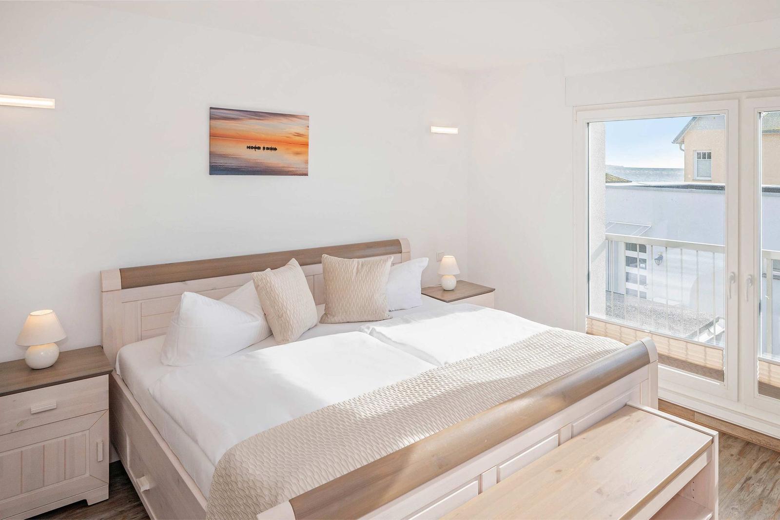 Schlafzimmer mit Doppelbett, Nachttischen und Balkontür mit Meerblick.
