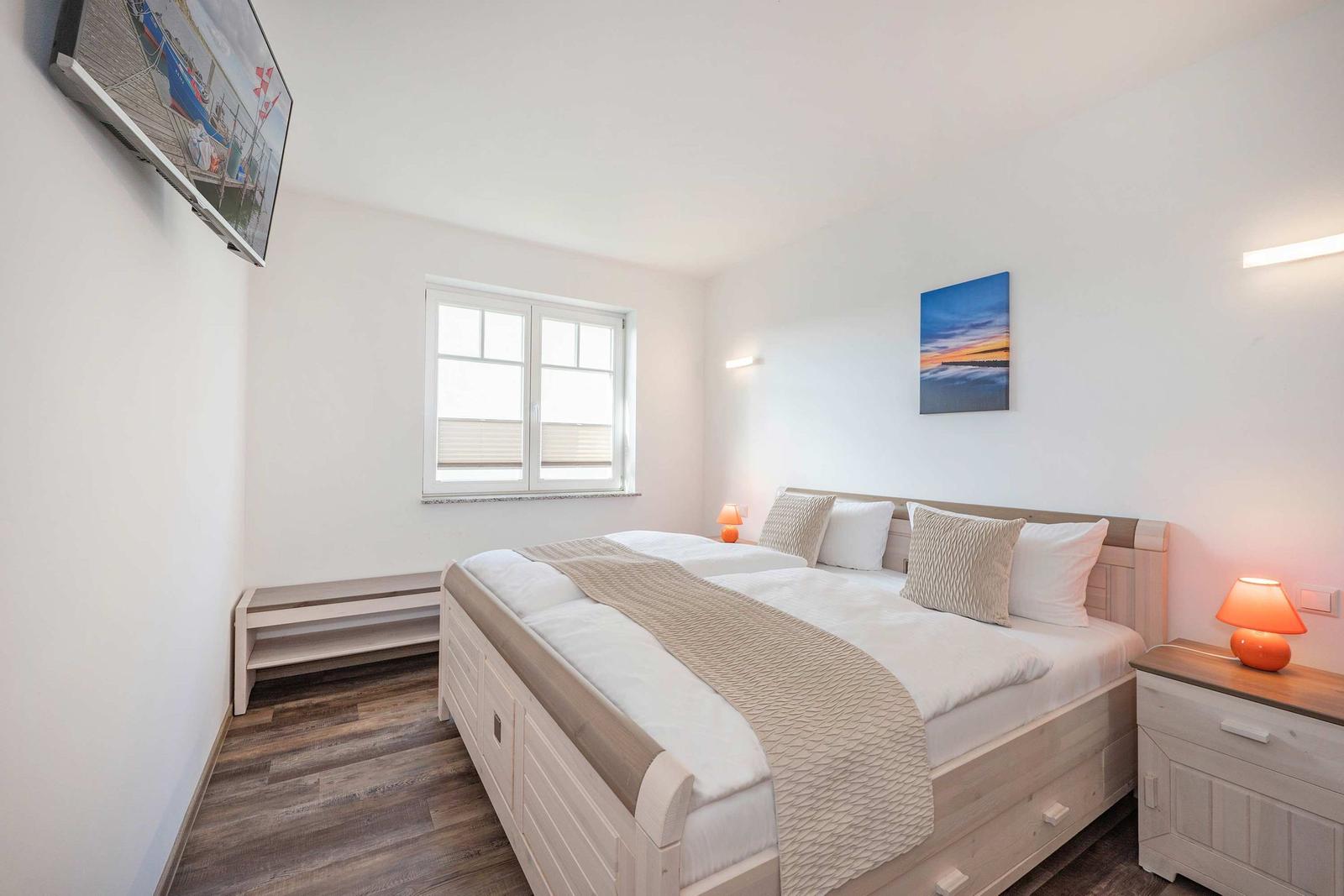 Bedroom with double bed, window, bedside table, and wall art.