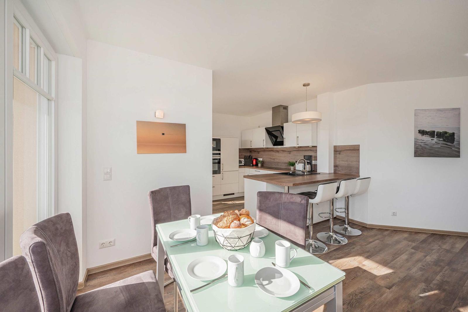 Dining area with table, chairs, and view into the kitchen with bar stools.