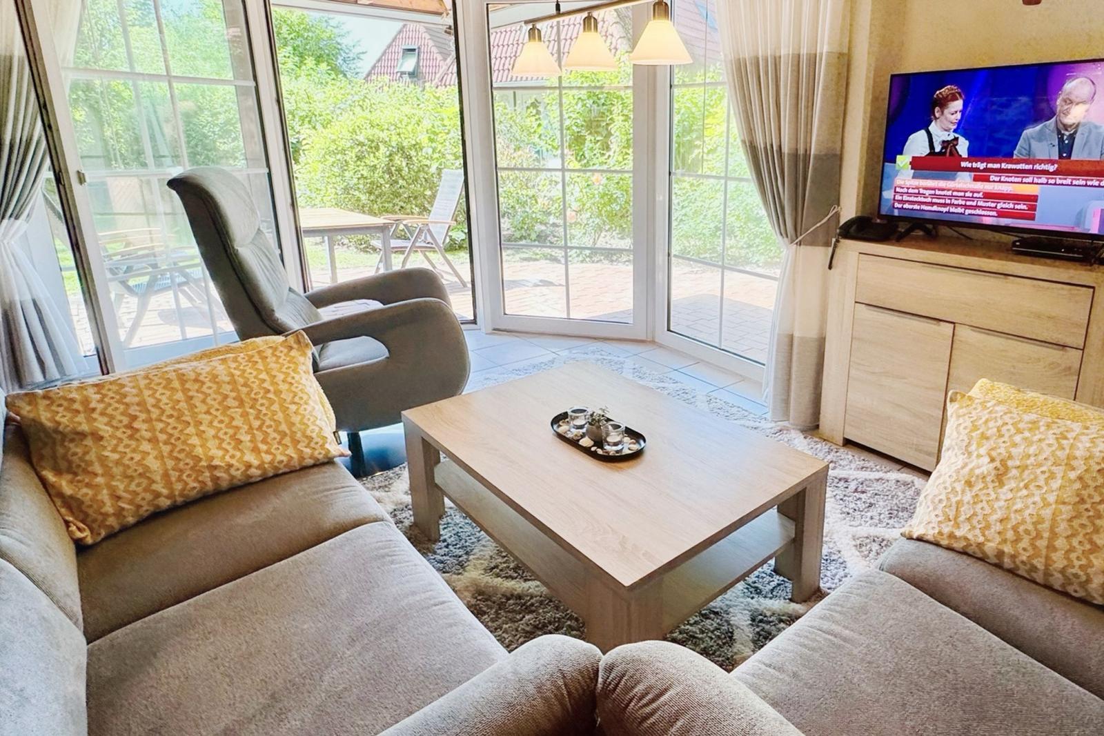 Living room with sofa, coffee table, and TV. Entrance to the garden.