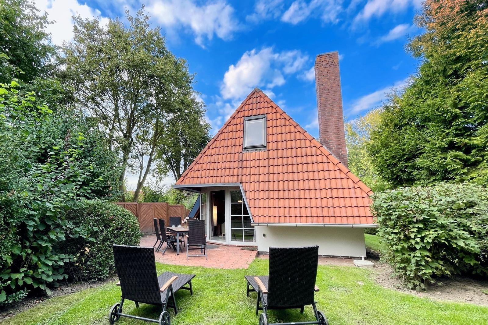 House with red roof, garden area, and two lounge chairs. Grill and terrace are available.