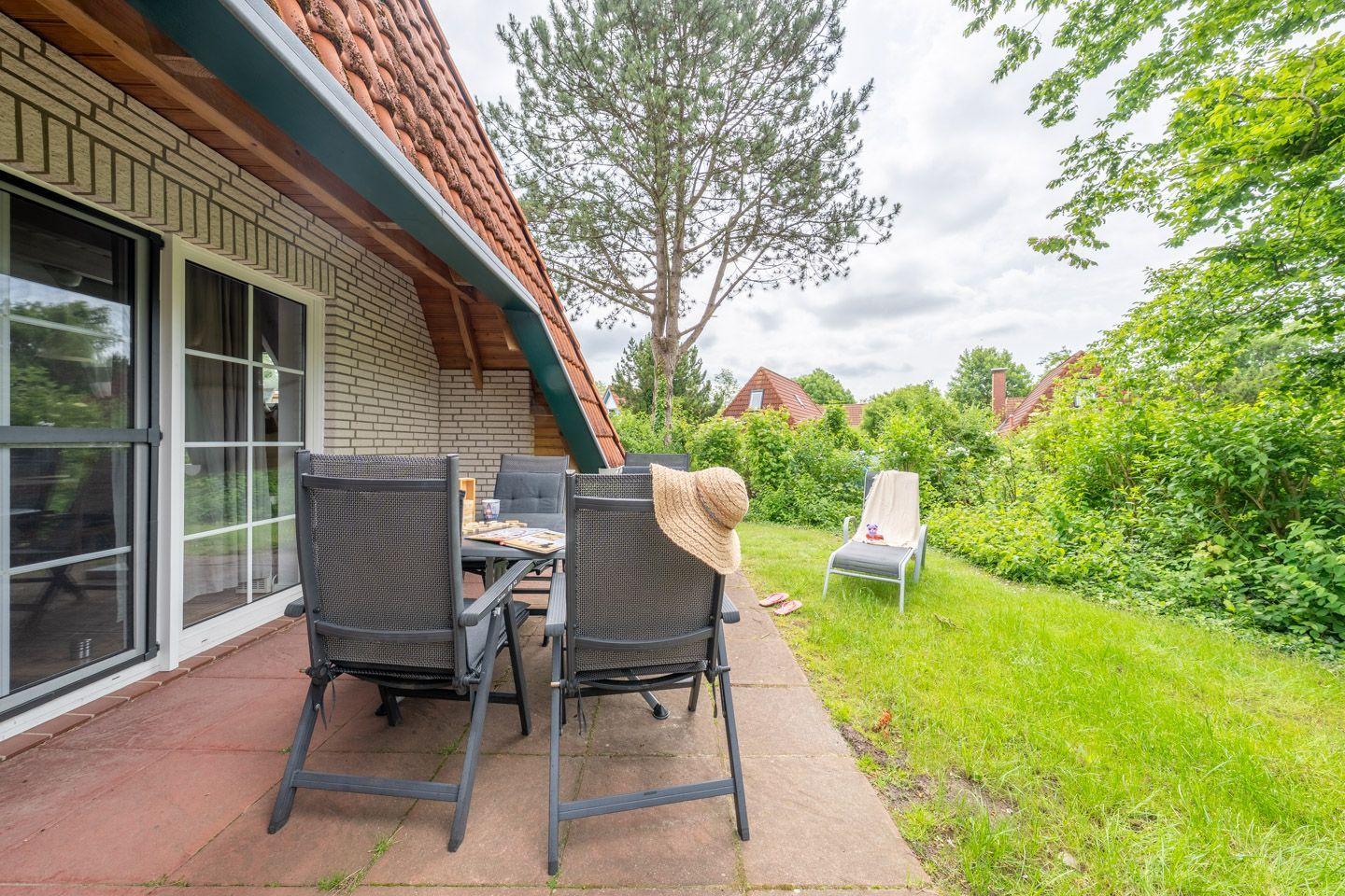 Terrasse mit Sitzgruppe, Garten und Blick auf Bäume.
