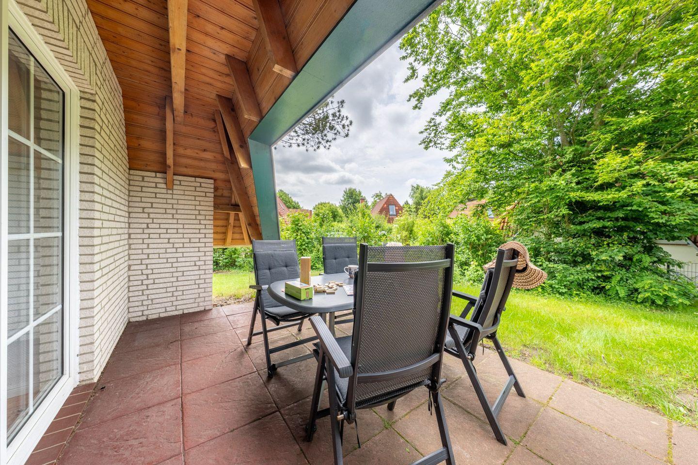 Terrasse mit Sitzgruppe, Blick auf grüne Landschaft und angrenzende Häuser.