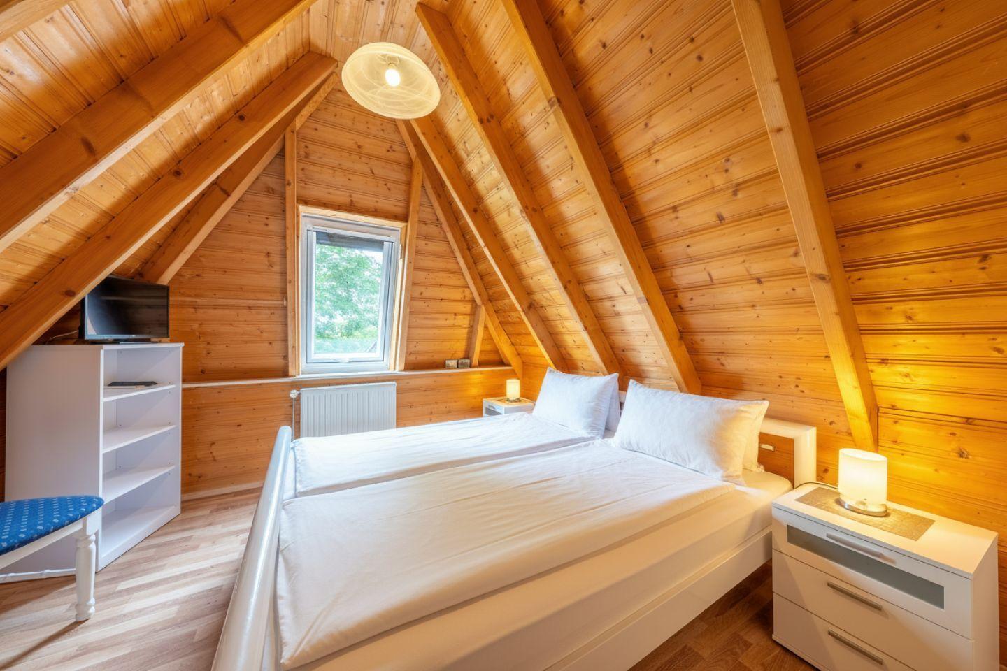 Bedroom with sloped ceiling, bed, nightstand, and window
