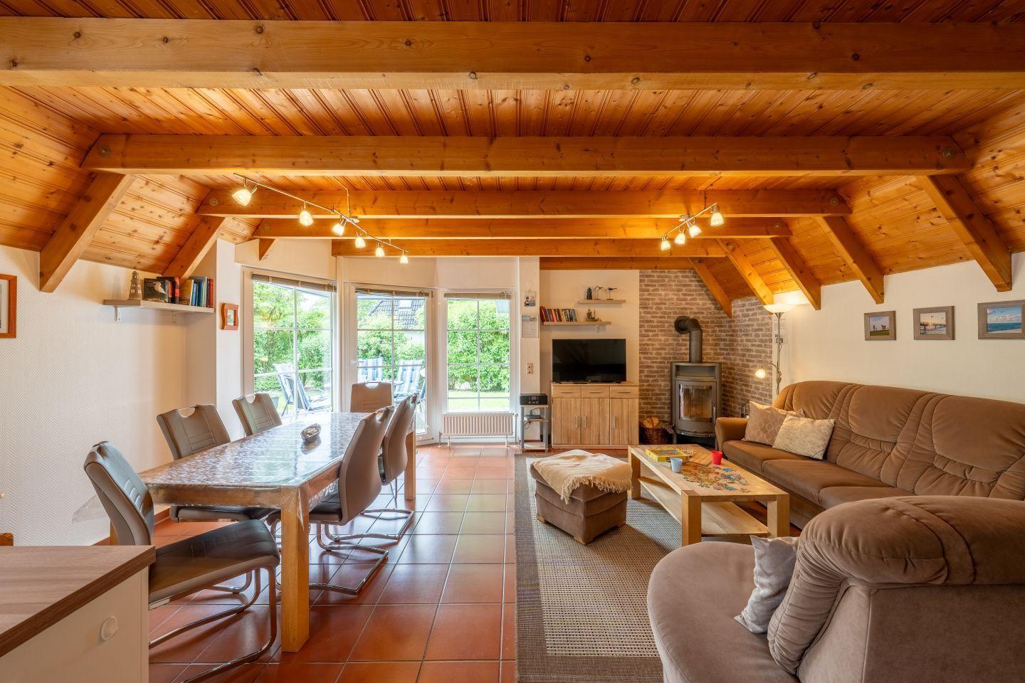 Living and dining area with wooden ceiling, sofa, dining table, and fireplace.