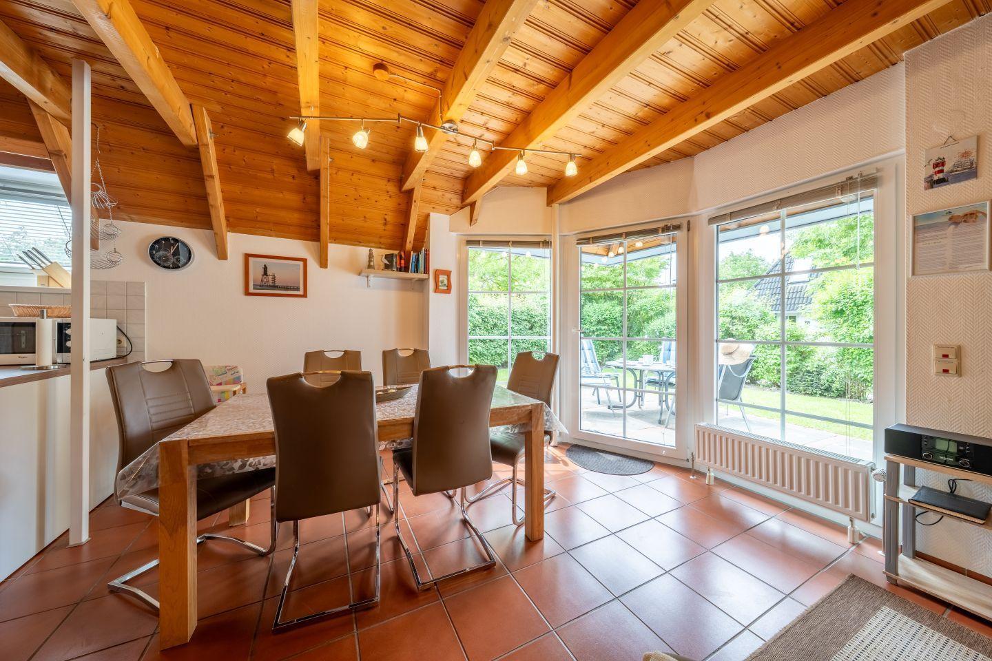 Dining room with wooden ceiling, table and chairs, view of garden.