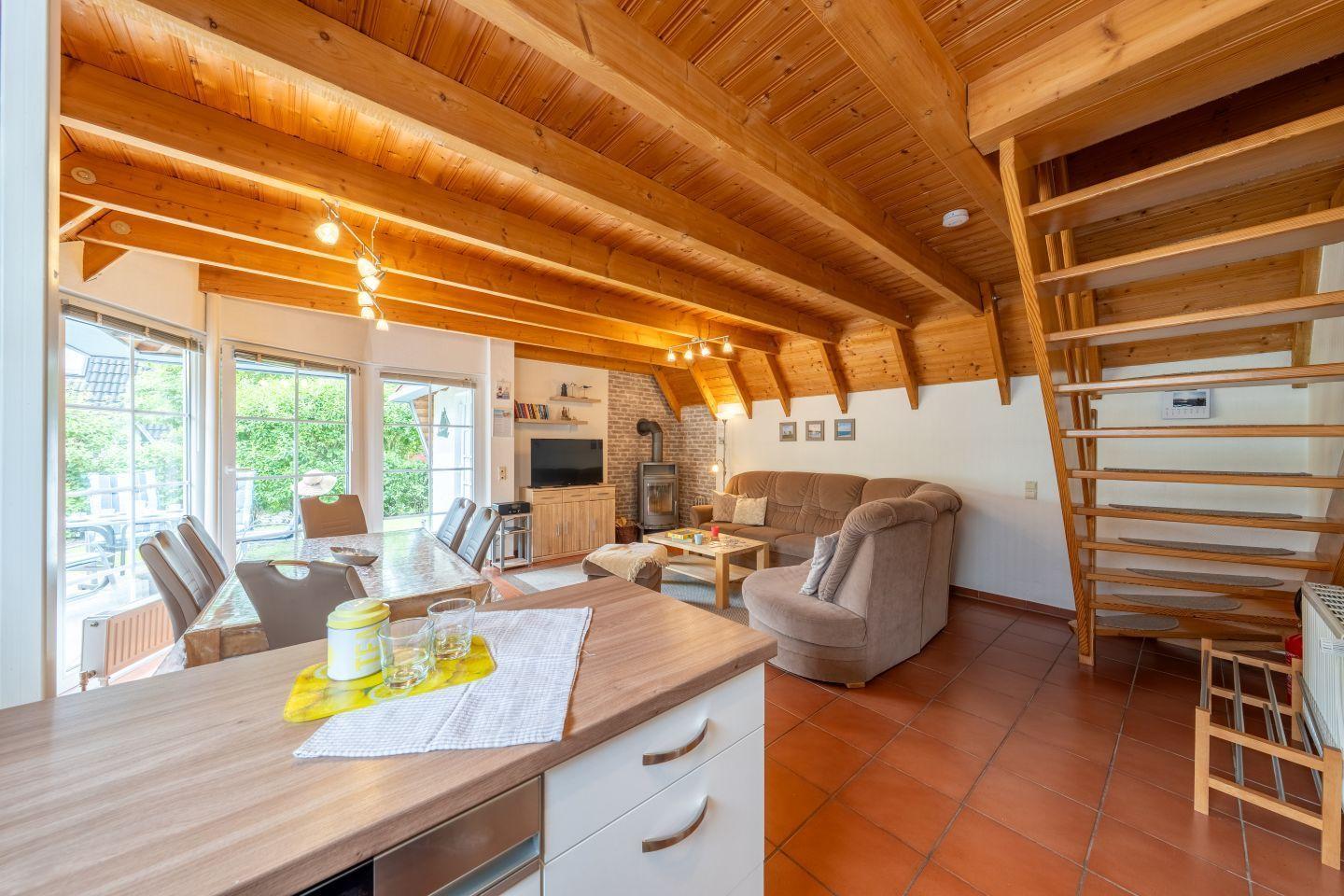 Living and dining area with wooden ceiling, sofa, armchair, and kitchen island.