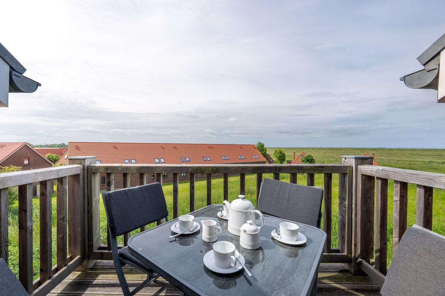 Terrasse mit Tisch und Stühlen, Blick auf Grünflächen und Gebäude