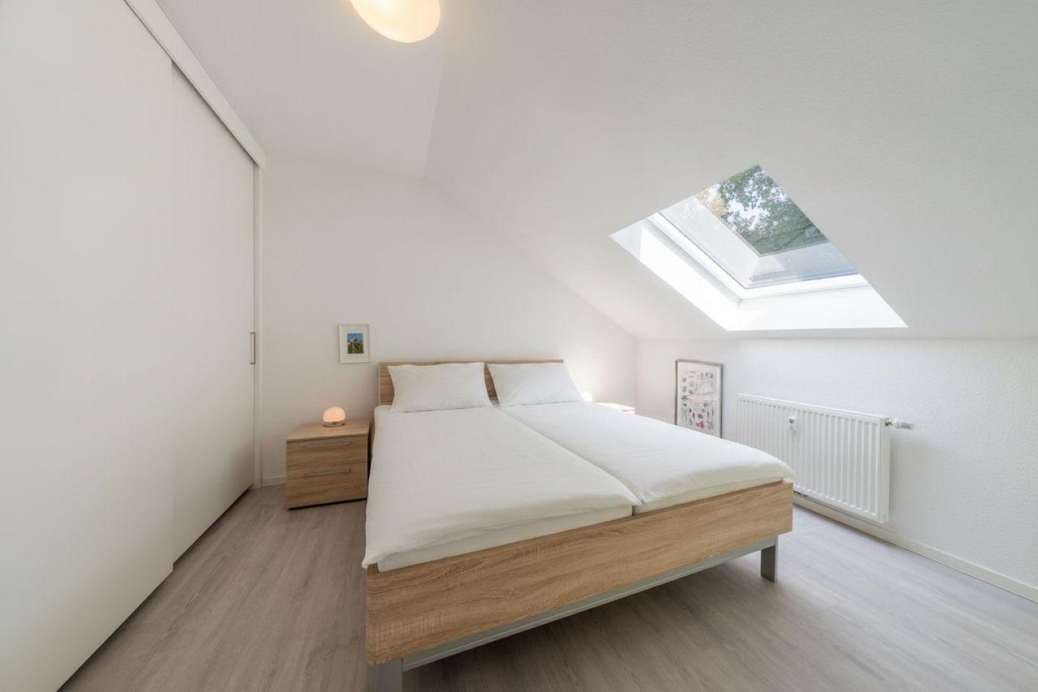 Schlafzimmer mit Doppelbett, Schwebetüren und Dachfenster.