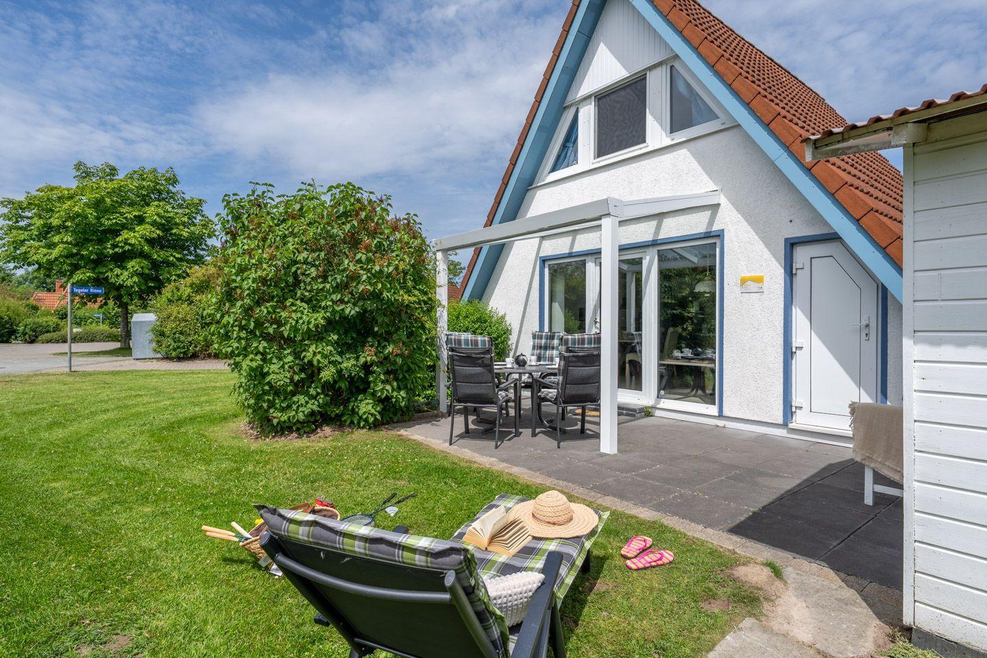 Haus mit Terrasse, Garten und Liegestuhl im Freien.