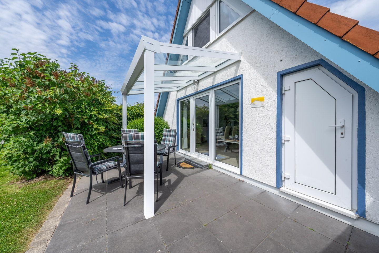 Terrasse mit Sitzgruppe unter Markise. Haustür und Glasfront zur Wohnung.
