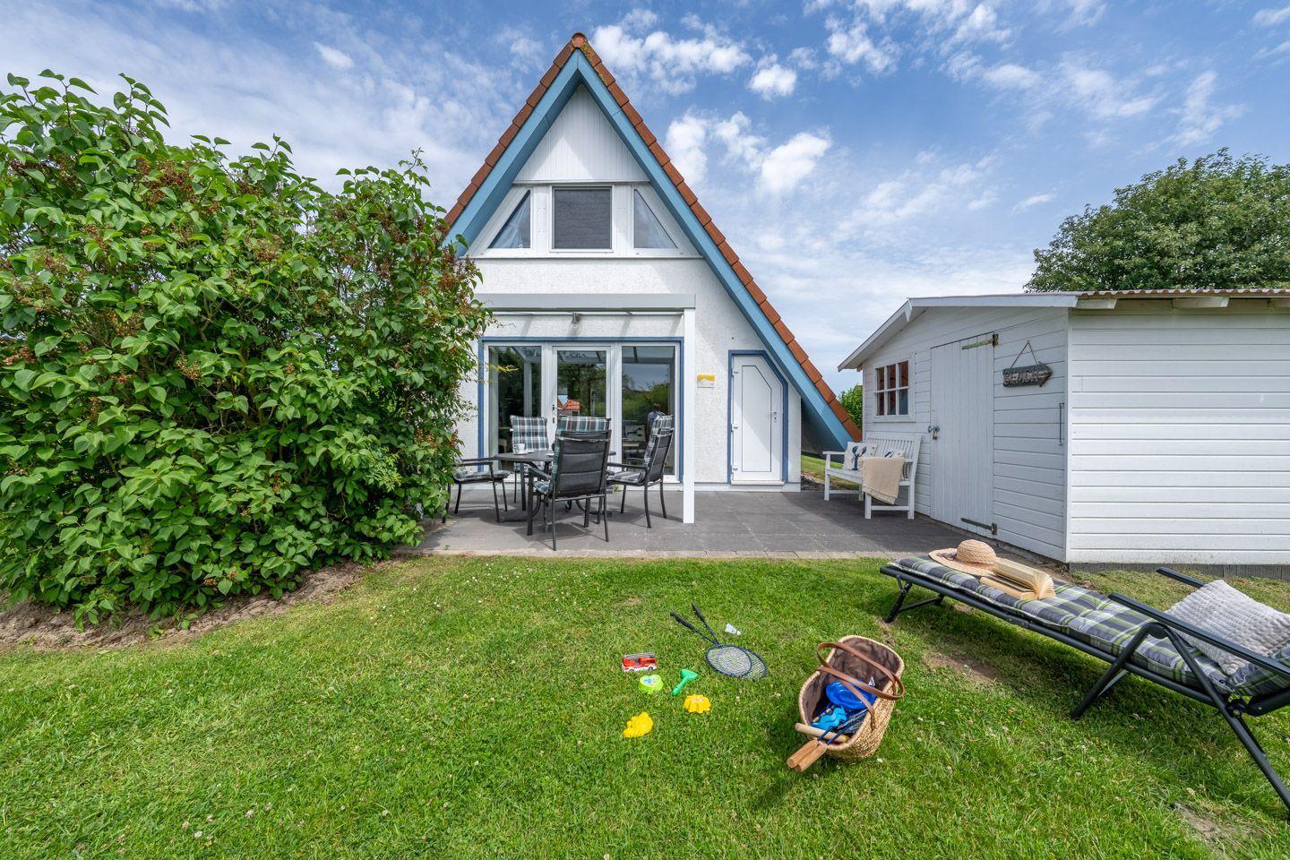 Haus mit Terrasse, Garten und Liege. Spielzeug und Sonnenschutz im Freien.