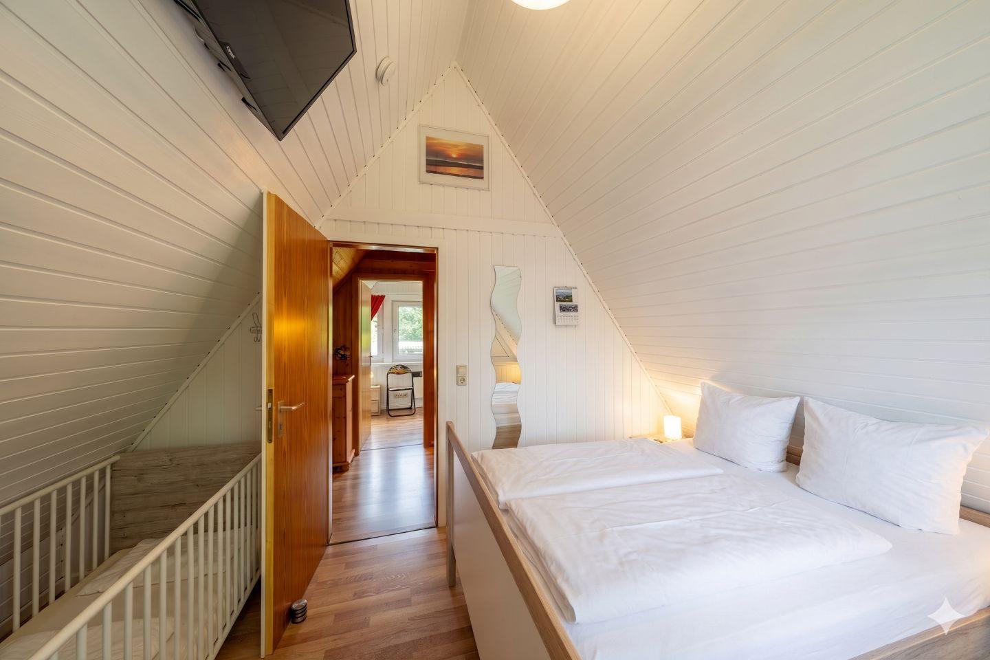 Bedroom with double bed, TV, and view into the hallway.