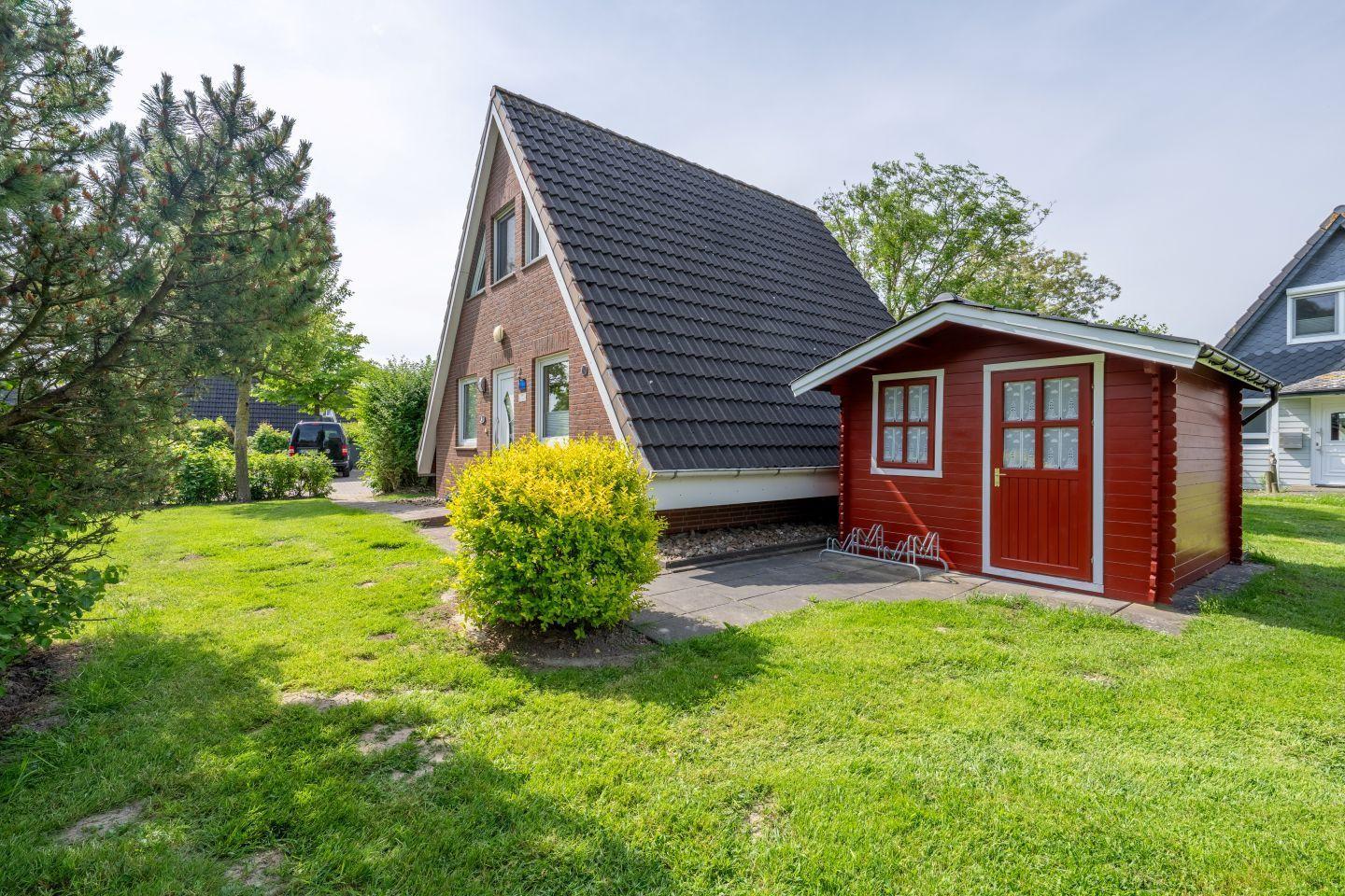 House with red wooden shed and green lawn. Roof tiles and windows are visible.