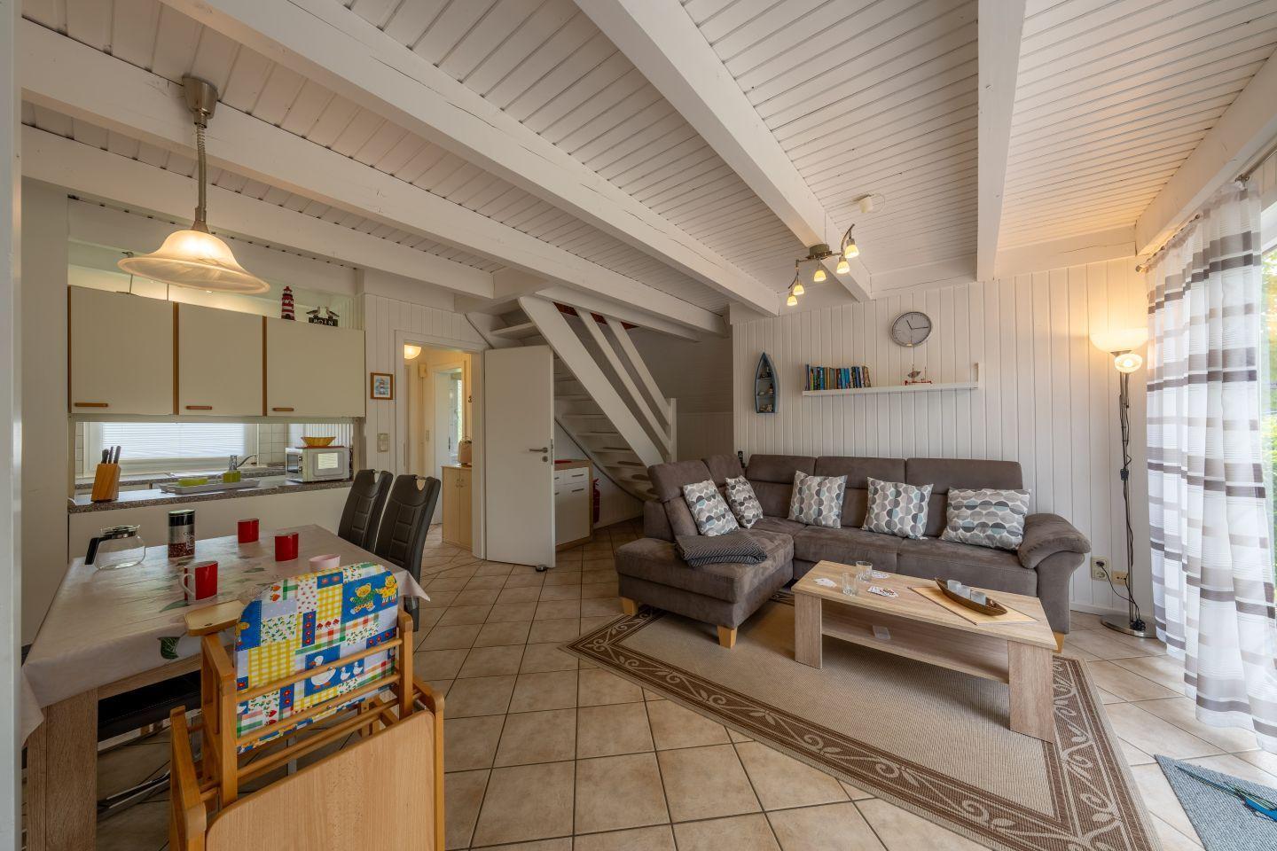 Living and dining area with sofa, table, and kitchen under high ceiling.