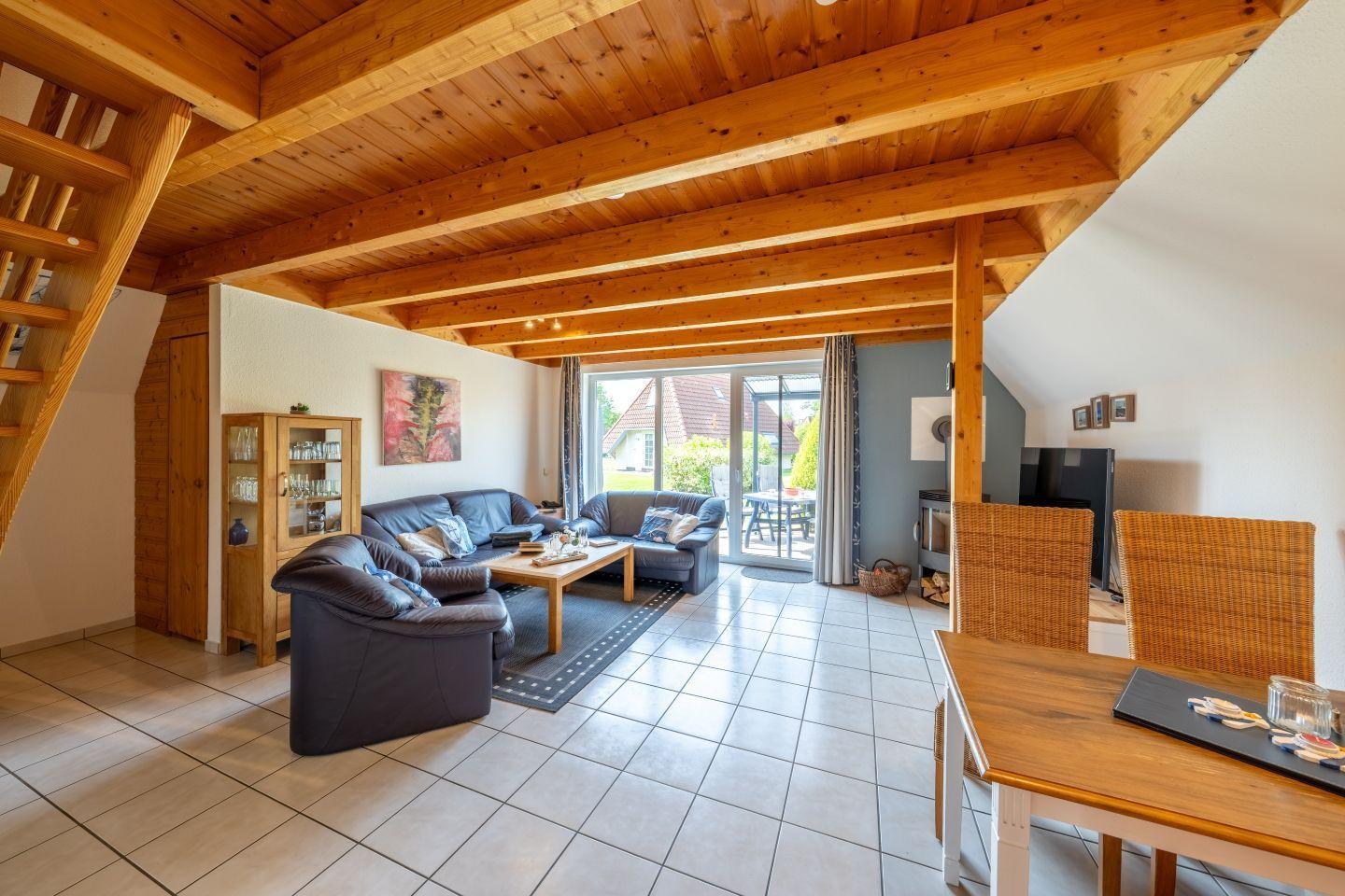 Wohn- und Essbereich mit Holzdecke, Sofa, Esstisch und Blick auf die Terrasse.