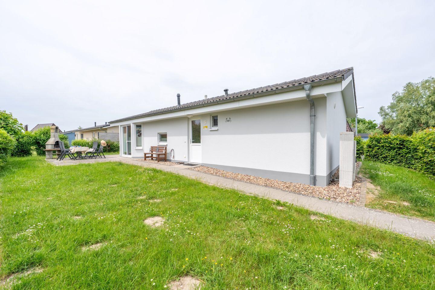 Wohnhaus mit Garten, Terrasse und Grillplatz. Einfahrt und Fenster sichtbar.