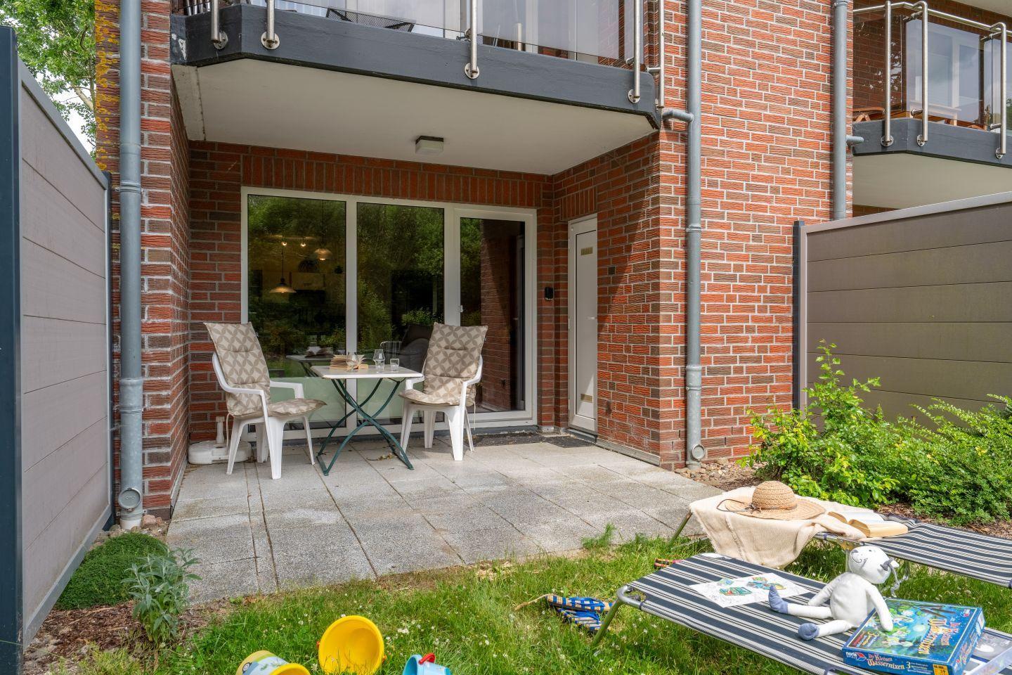 Terrace with table and chairs, garden with lounge chair and childrens toys.