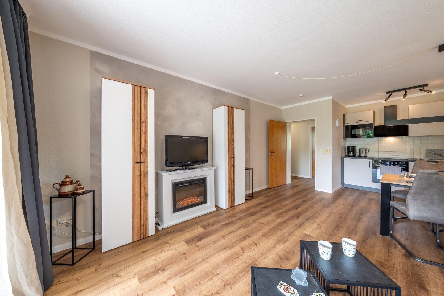 Wohn- und Küchenbereich mit Holzboden, Fernseher und Kamin.