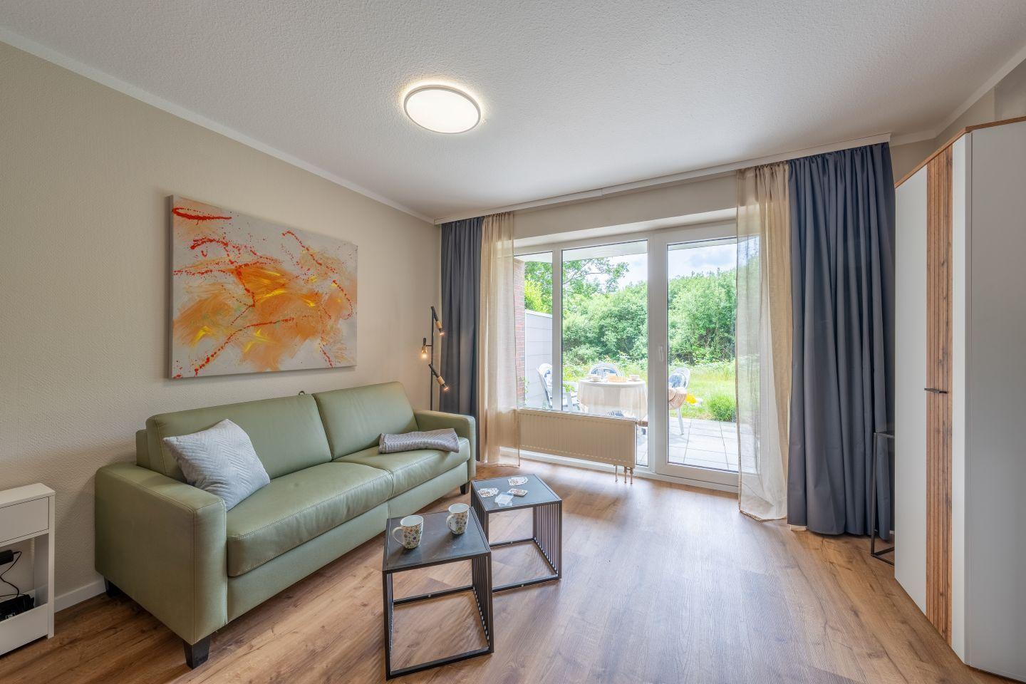 Wohnzimmer mit Sofa, Tisch und Blick auf die Terrasse.
