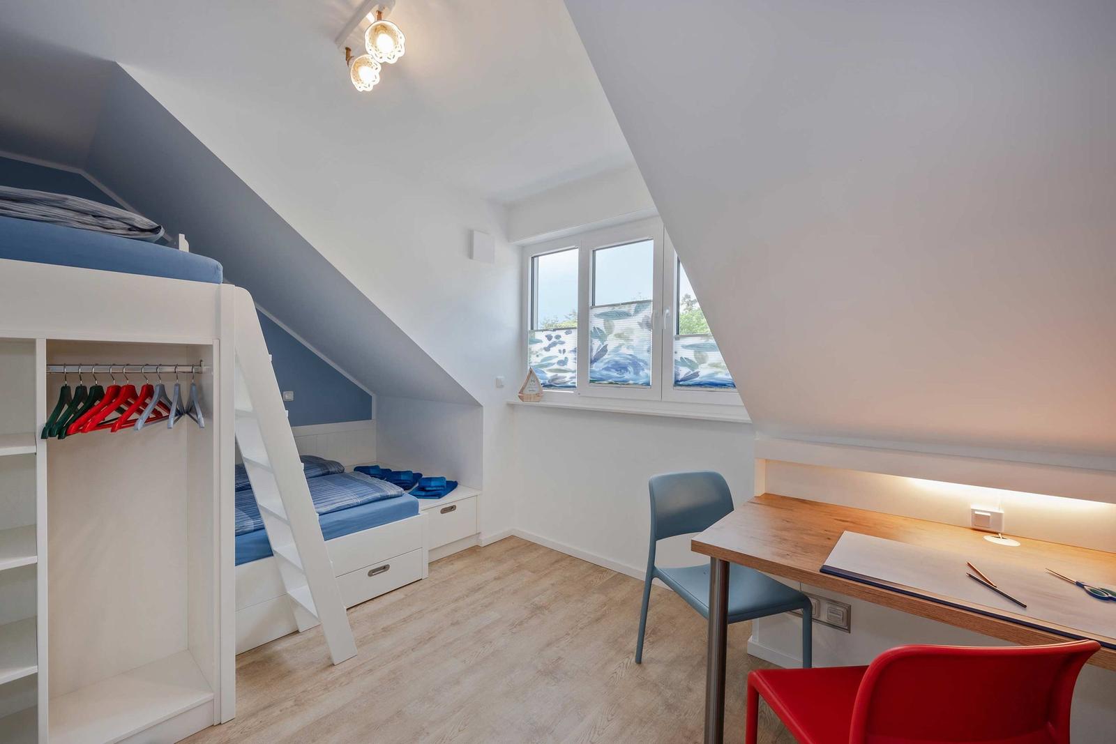 Kinderzimmer mit Doppelstockbett, Schreibtisch und Fenster mit Blick nach draußen.