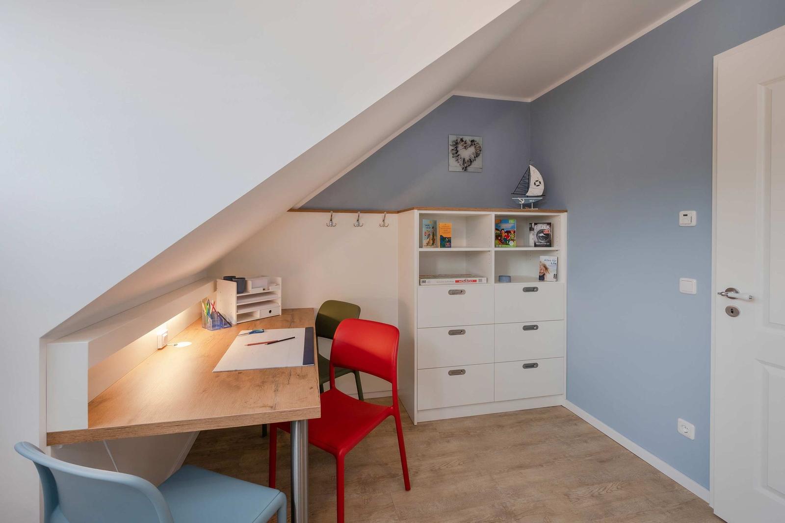 Ein Arbeitszimmer mit Schreibtisch, Stühlen und einem weißen Schrank unter einem Dach